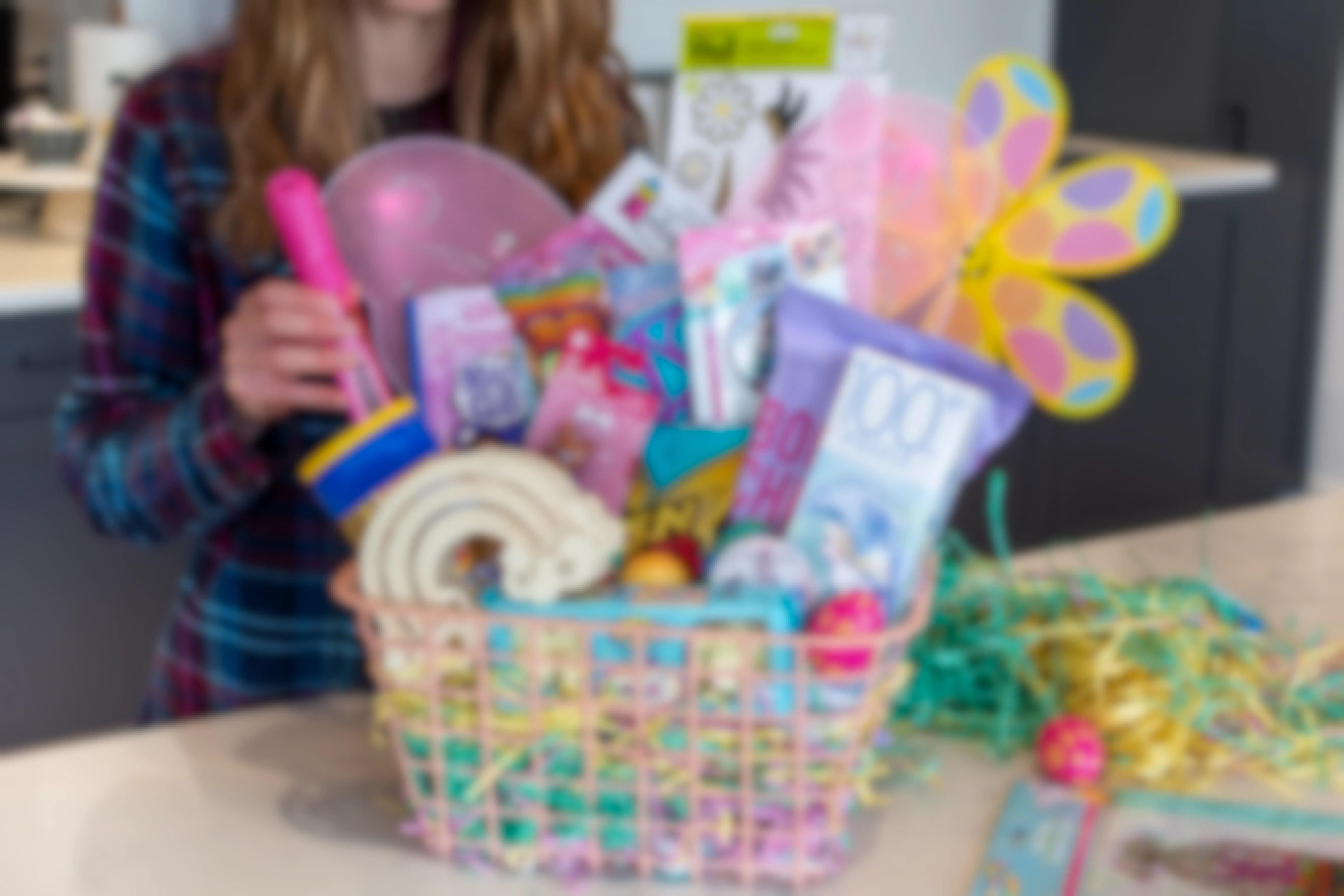 A woman stands behind the counter arranging items inside a large pink Easter basket.