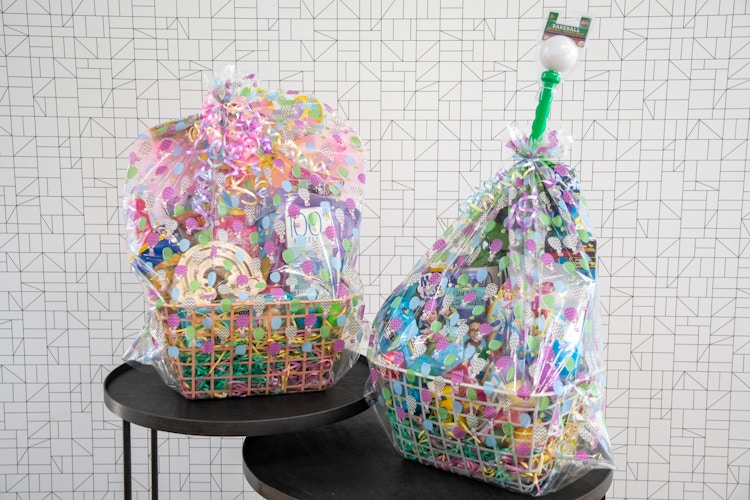 Two large Easter baskets wrapped in Easter themed basket bags sitting on and tables