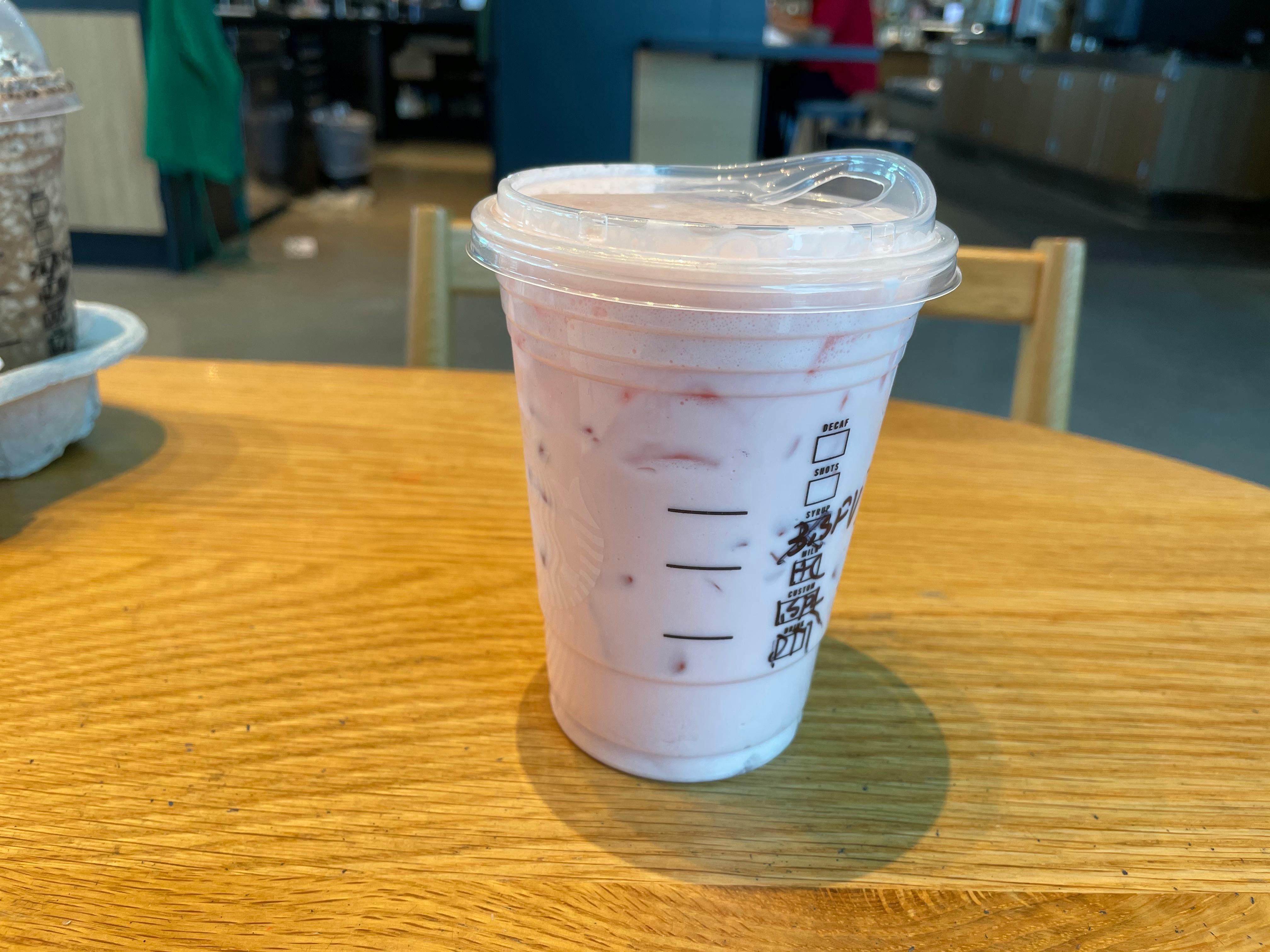 A Starbucks Grande Pink Drink sitting on a table inside Starbucks.