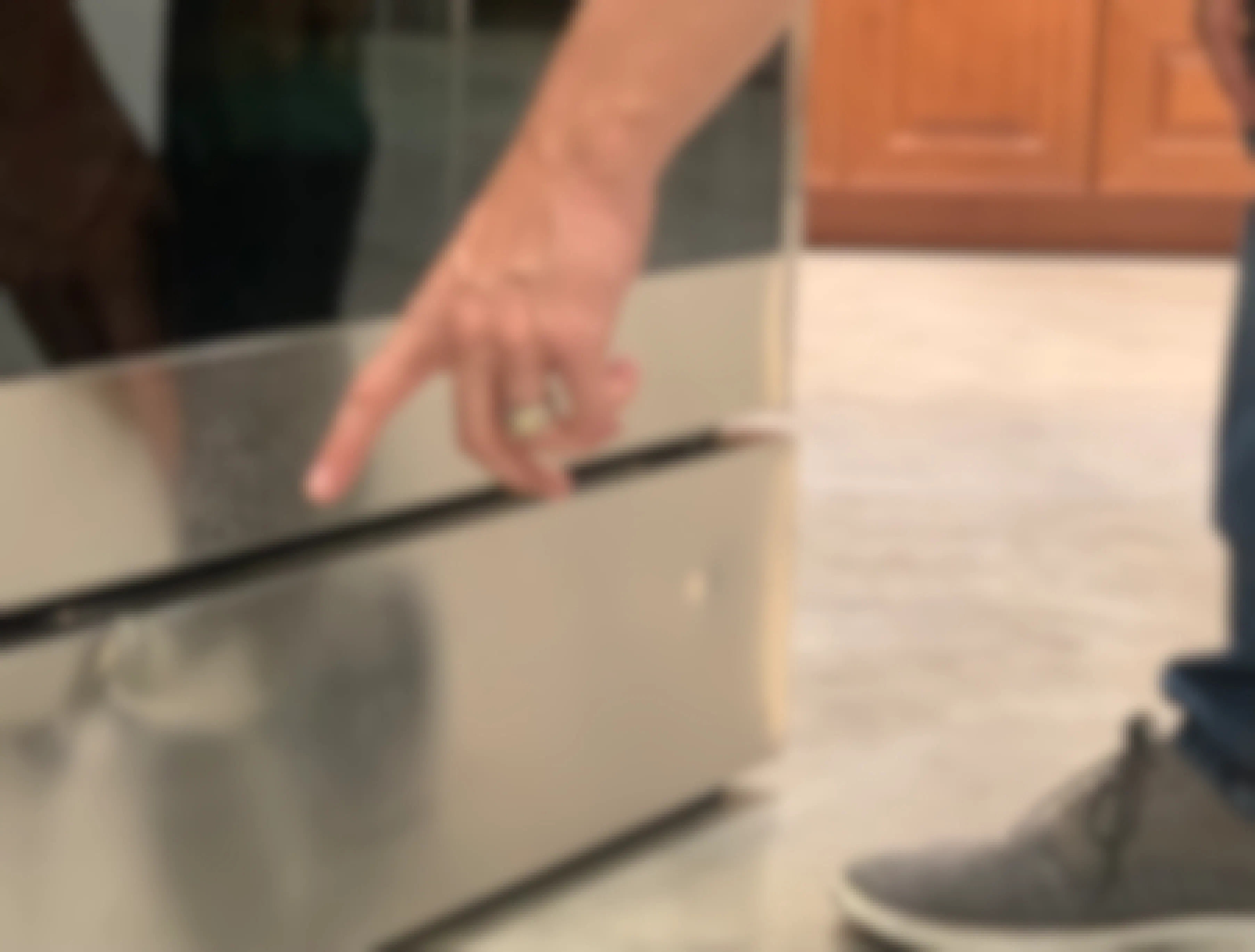 Man's hand pointing at dent on damaged appliance