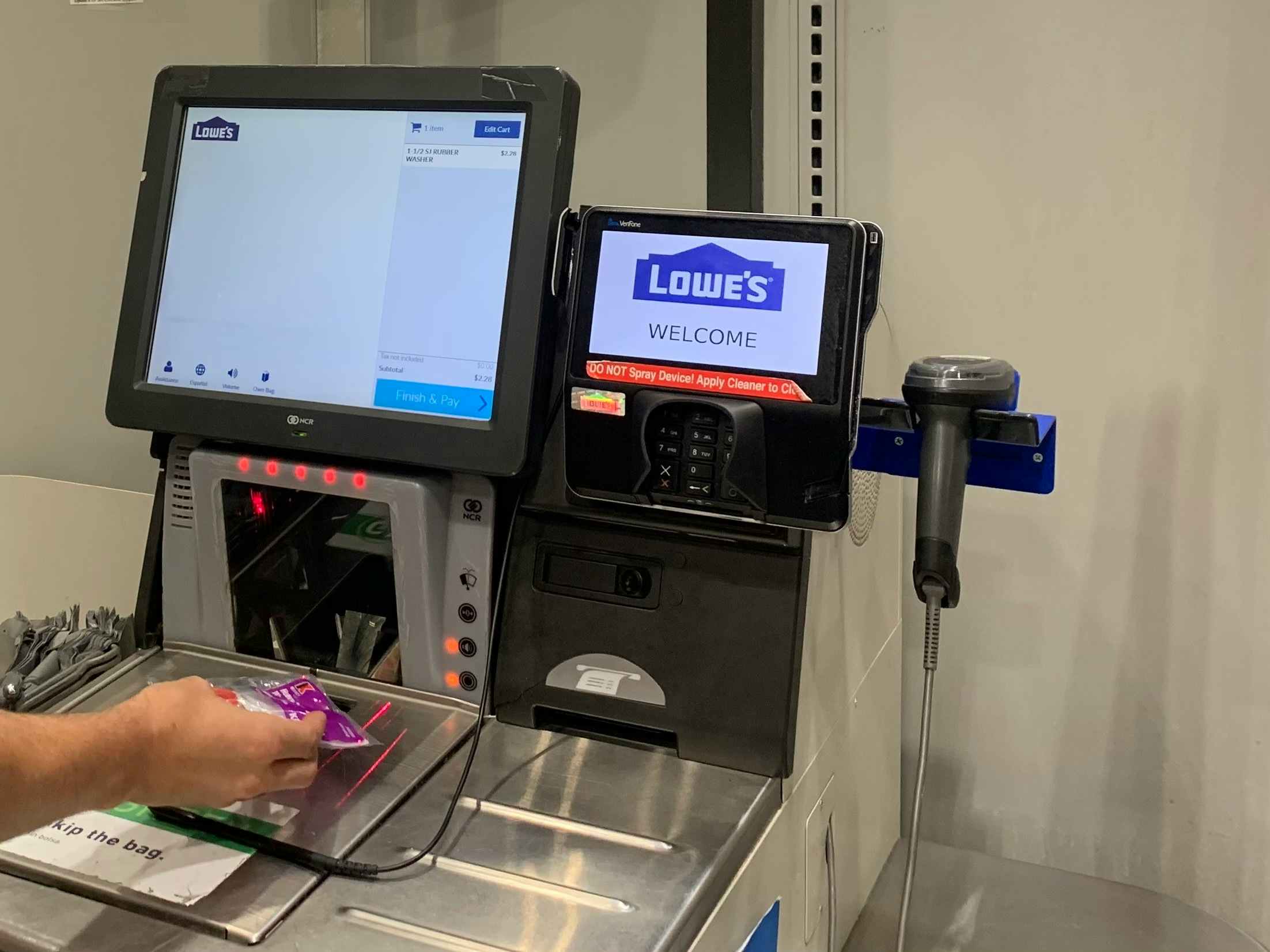 A person scanning an item at the Lowe's self checkout scanner.
