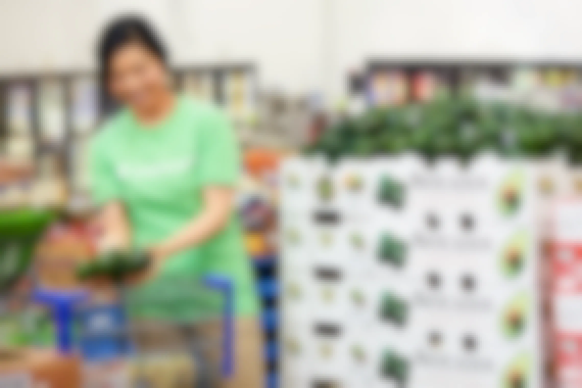 A woman in an Instacart shirt, putting avocados in a shopping cart inside Sam's Club