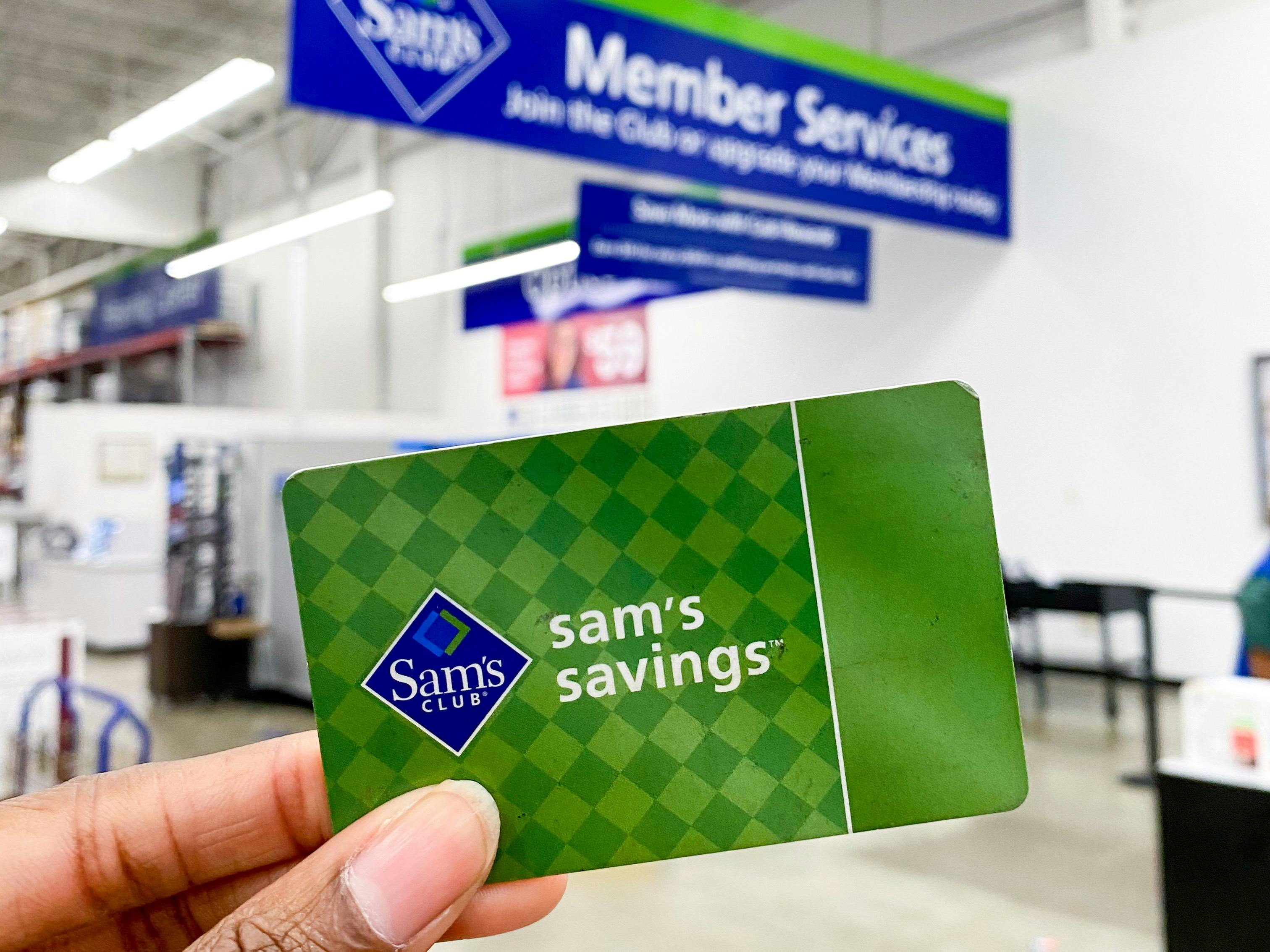 A person holding a Sam's Club gift card in front of customer service.