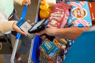 A Sam's Club Employee scanning a barcode on an customers phone to check them out with a scan and go order.