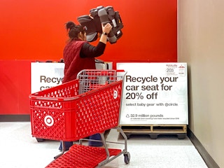 target employee placing car seats into box for trade-in event in store