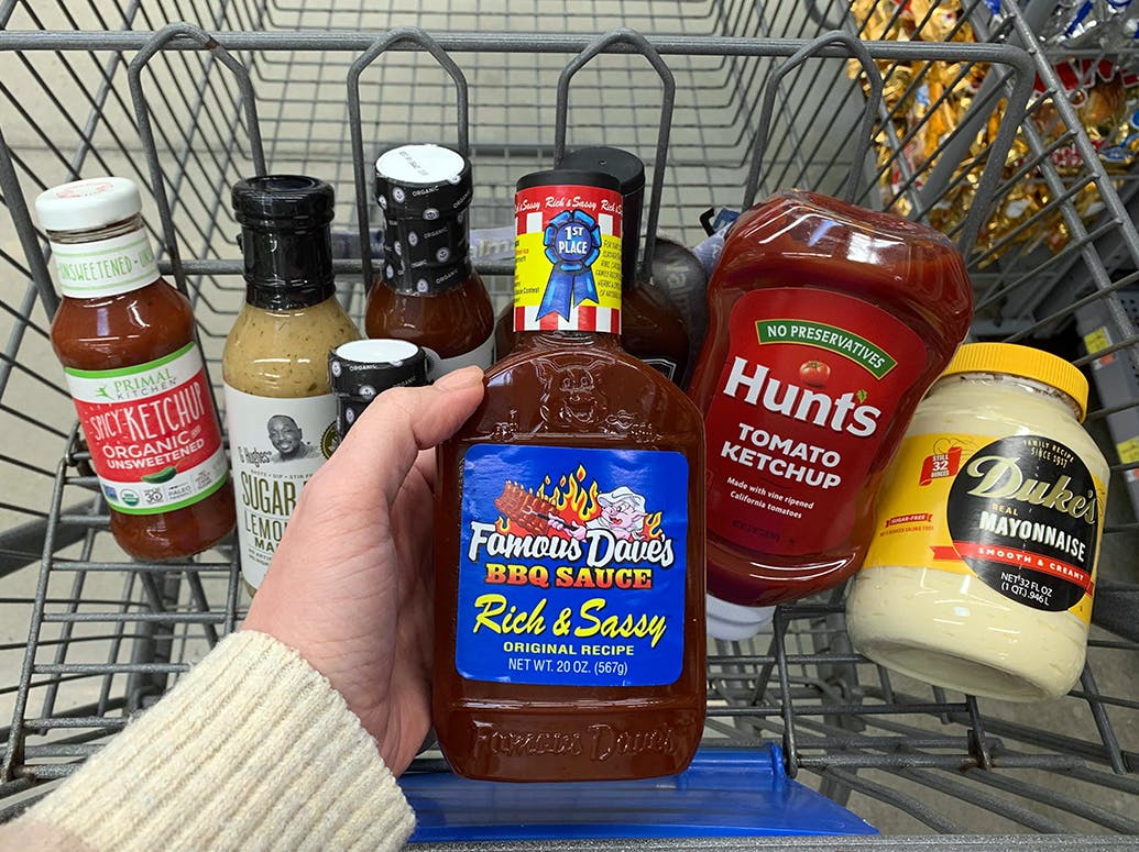 Someone putting condiments into a shopping cart