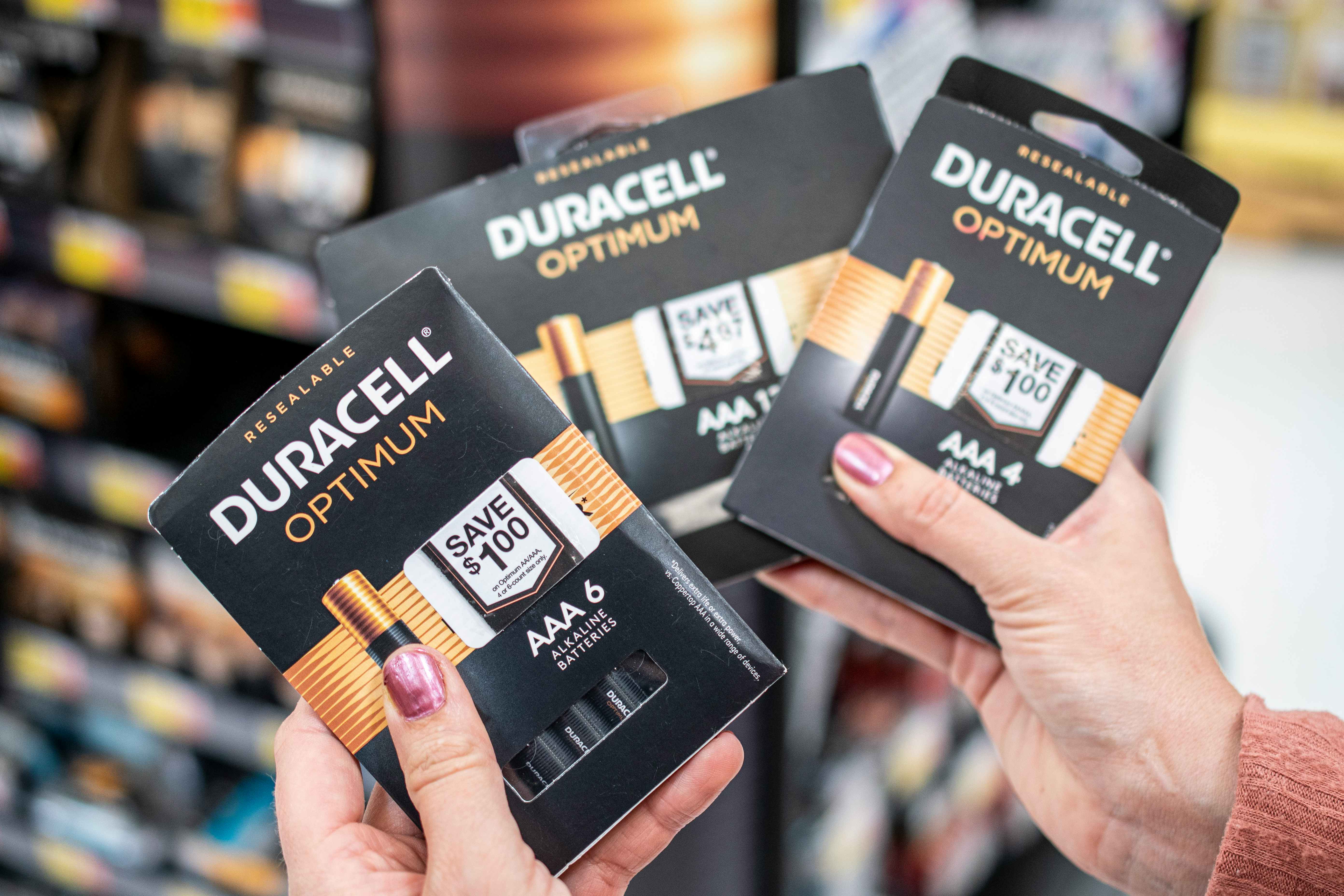 A person holding packages of Duracell Optimum batteries