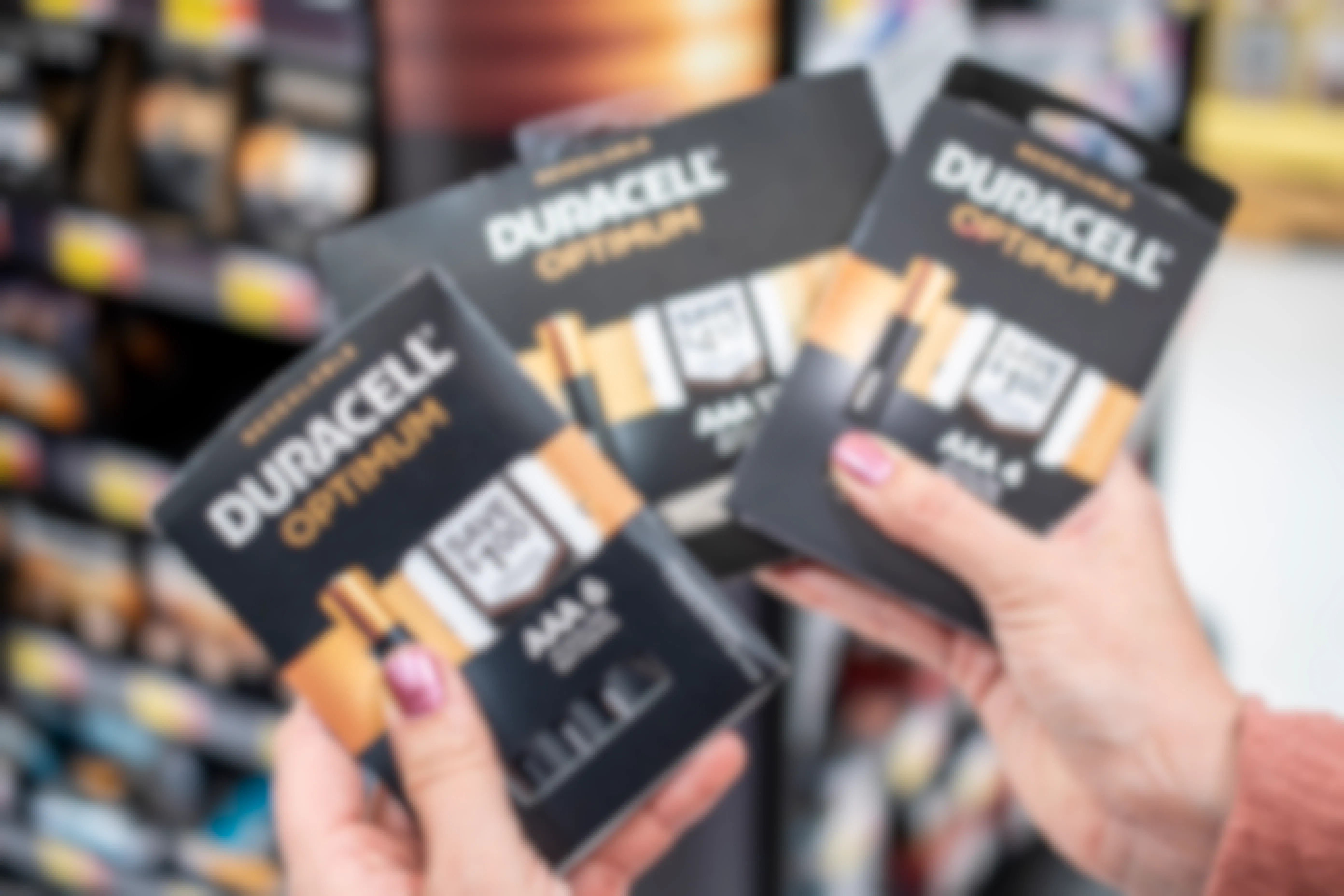 A person holding packages of Duracell Optimum batteries