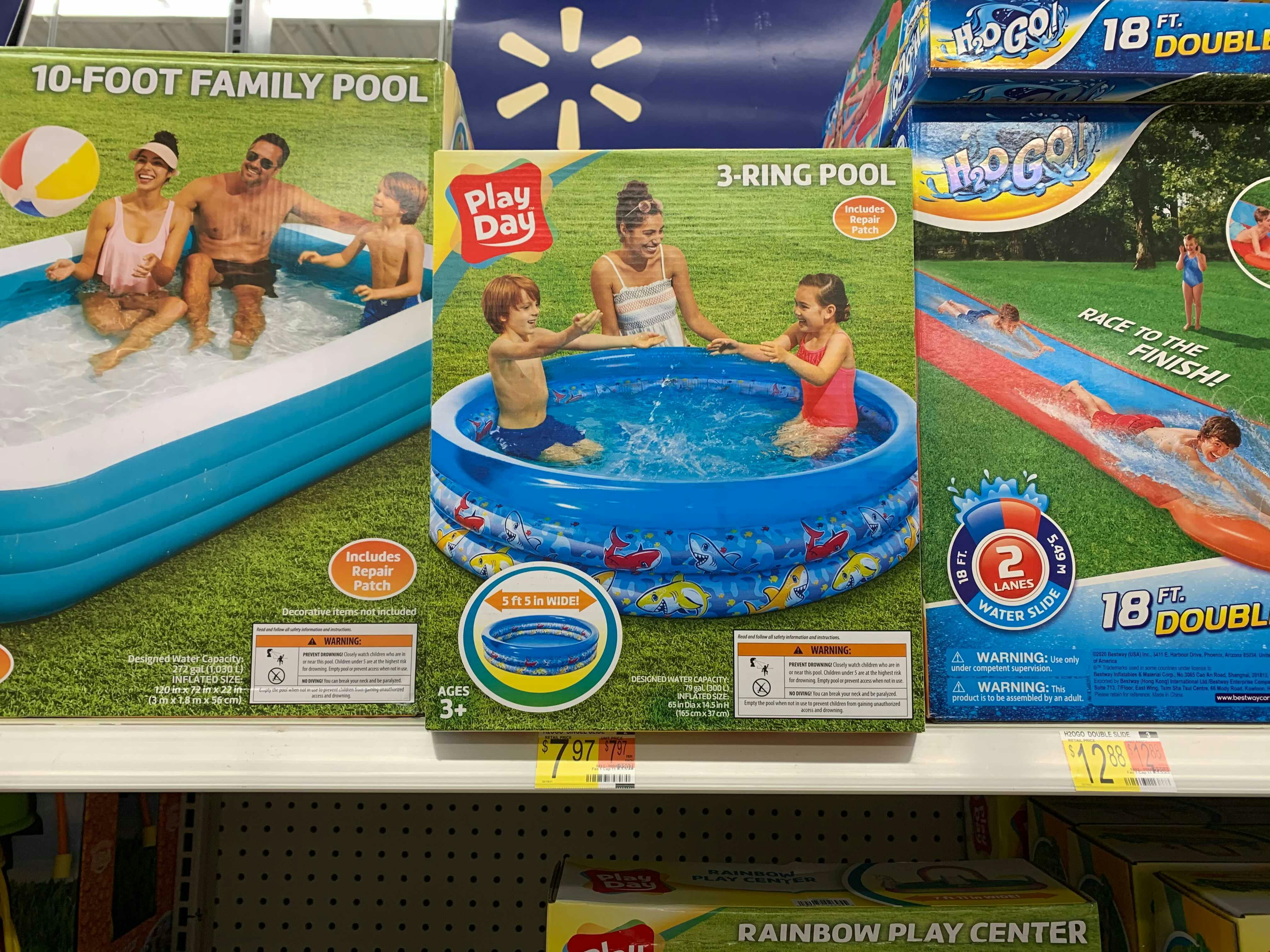 Some Play Day inflatable pools and water slide on a shelf at Walmart.