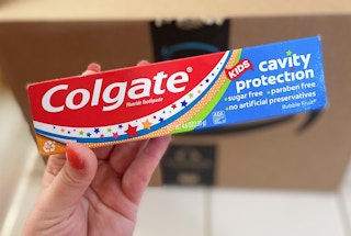 hand holding colgate cavity protection kids toothpaste in front of an amazon box
