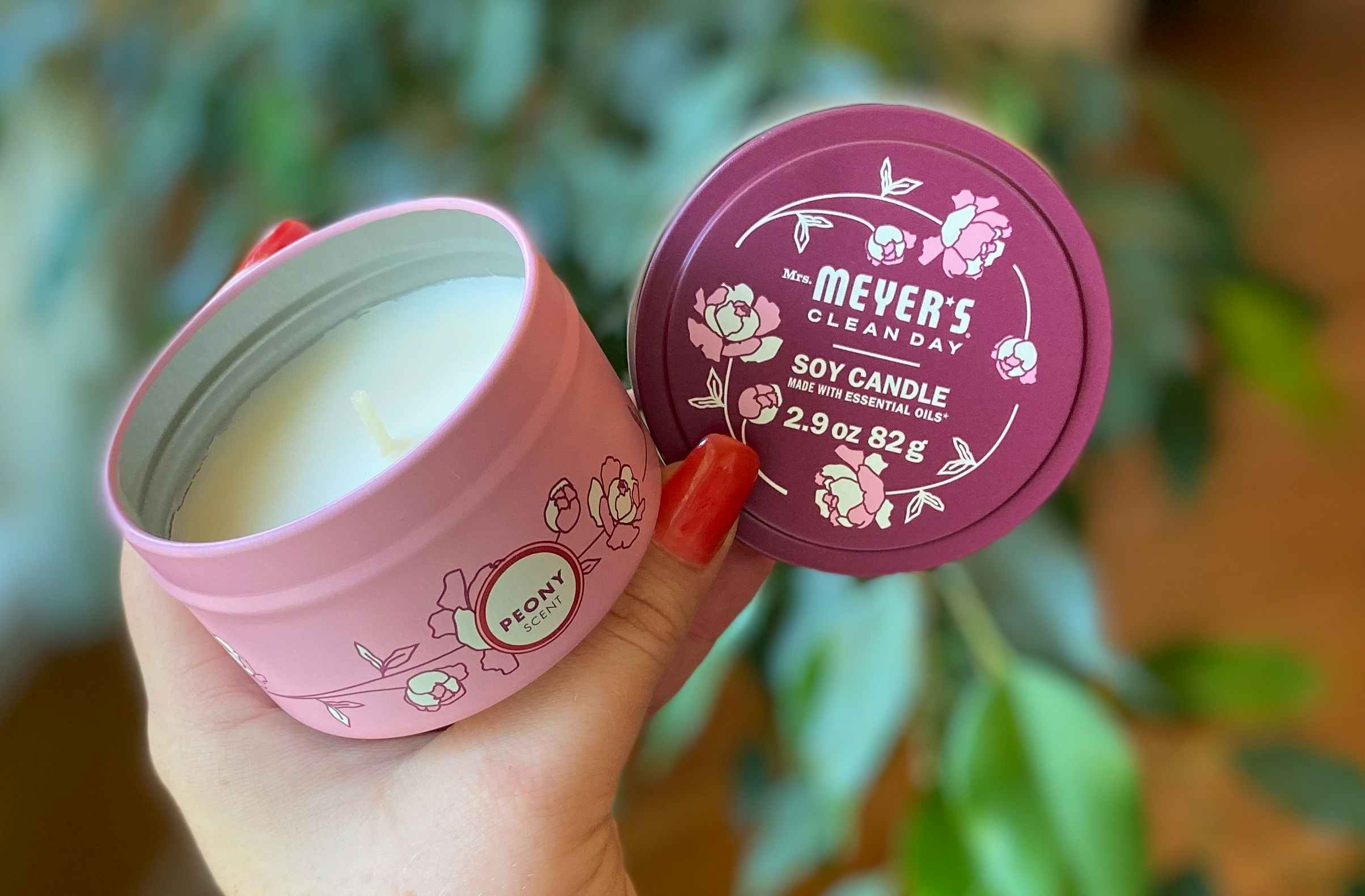 hand holding mrs meyers clean day soy peony scented candle