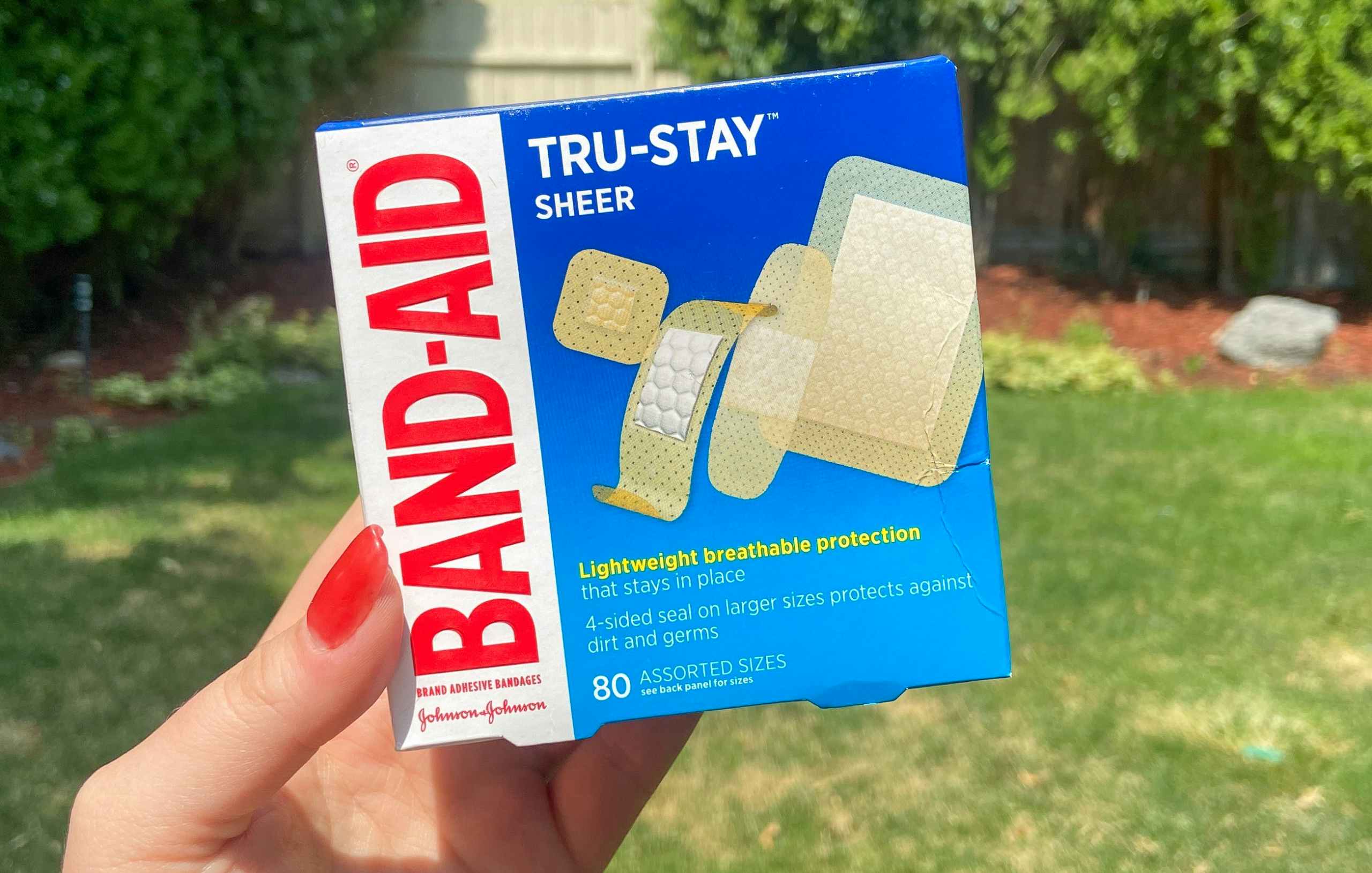 hand holding band aid true stay sheer bandages outdoors