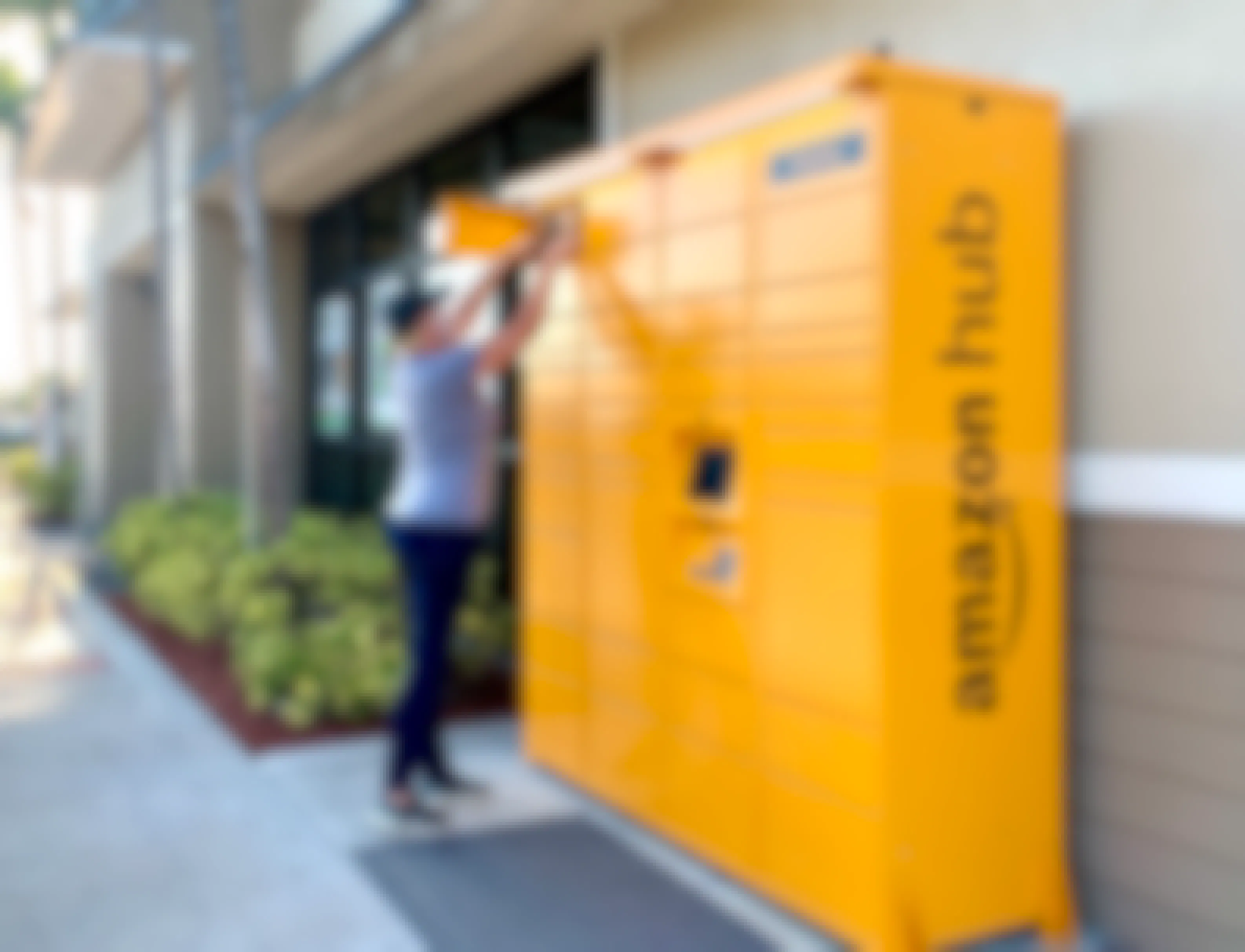 A woman taking an Amazon package out of an Amazon hub locker.