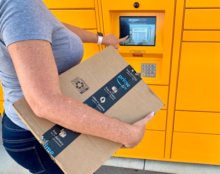 person holding an amazon box with looking at amazon locker keypad