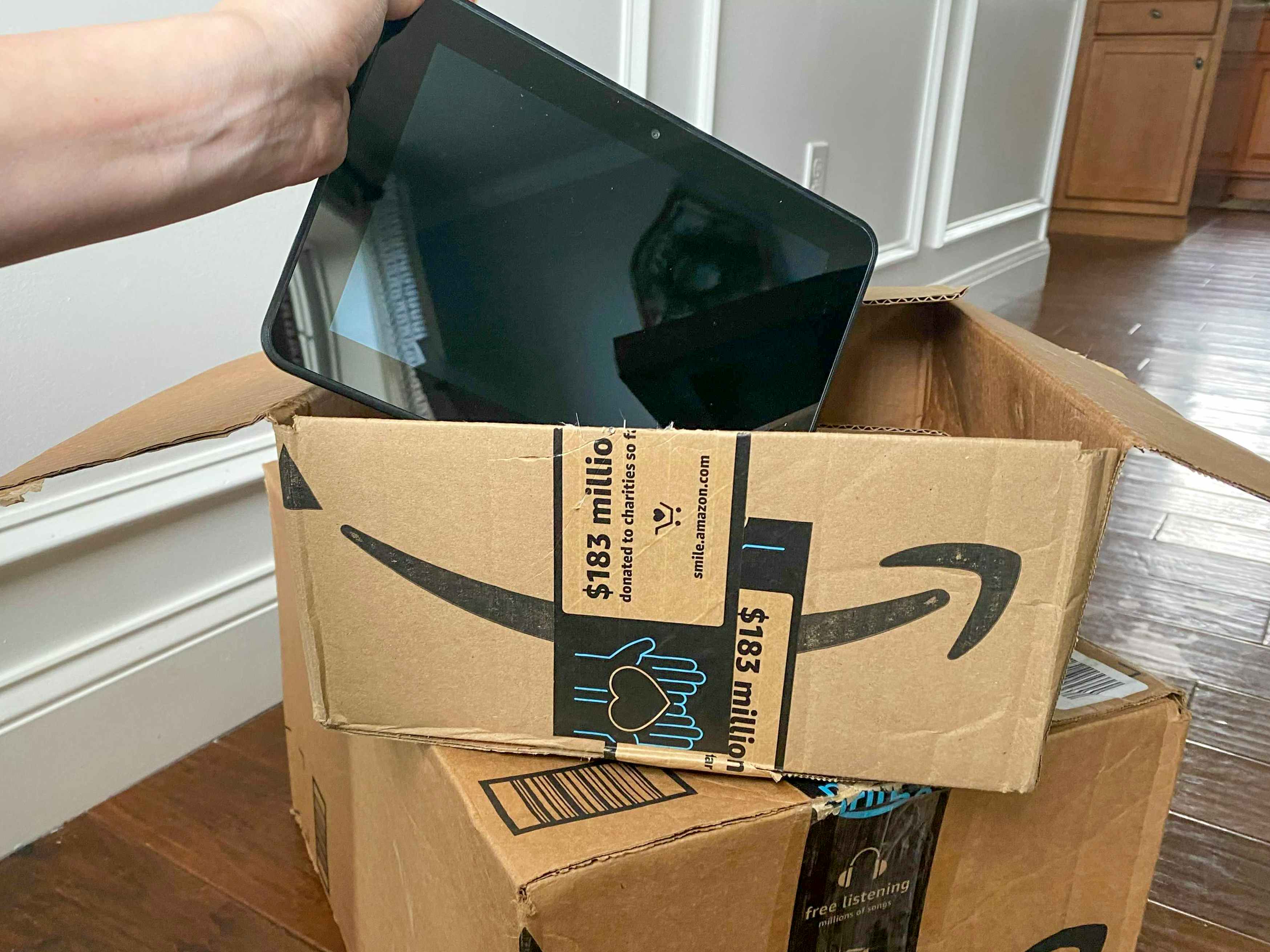 An Amazon fire tablet being put into an Amazon box.