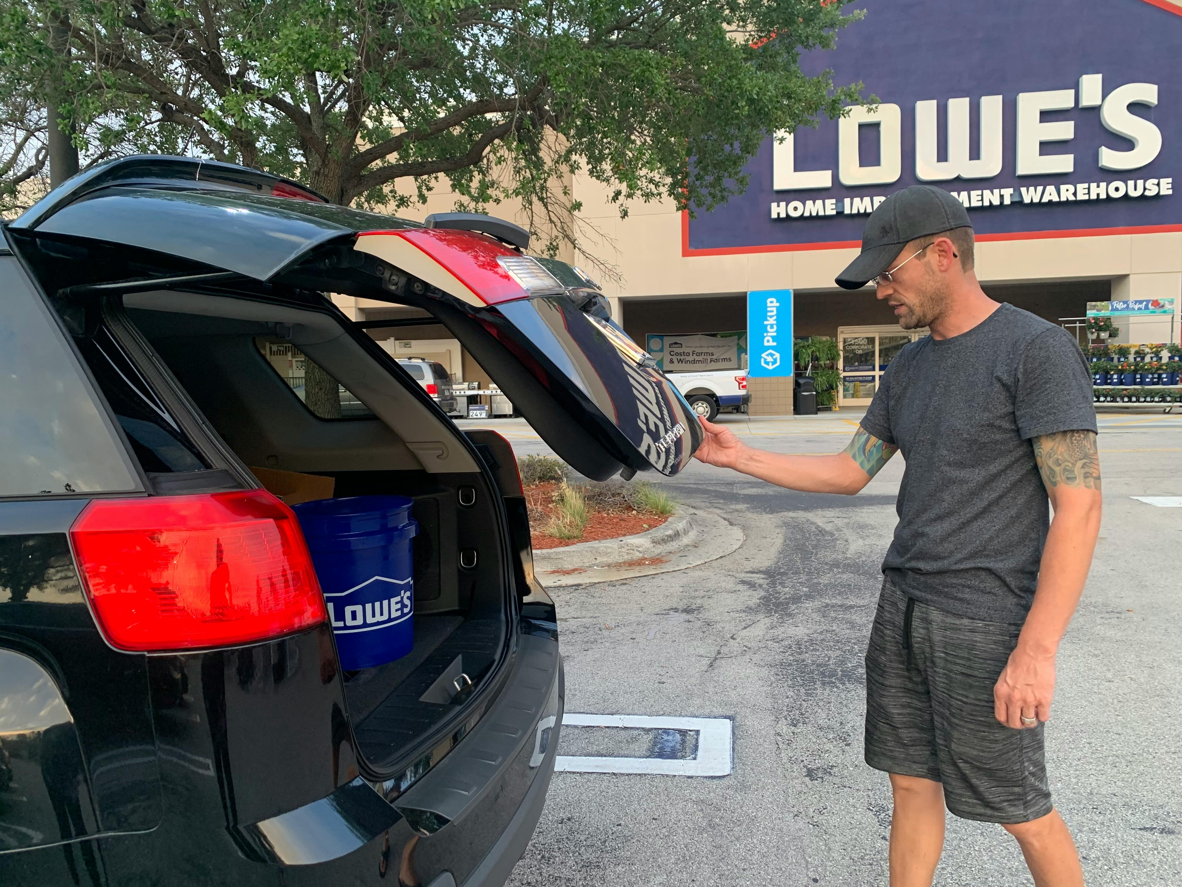 man closing trunk in parking lot of lowes