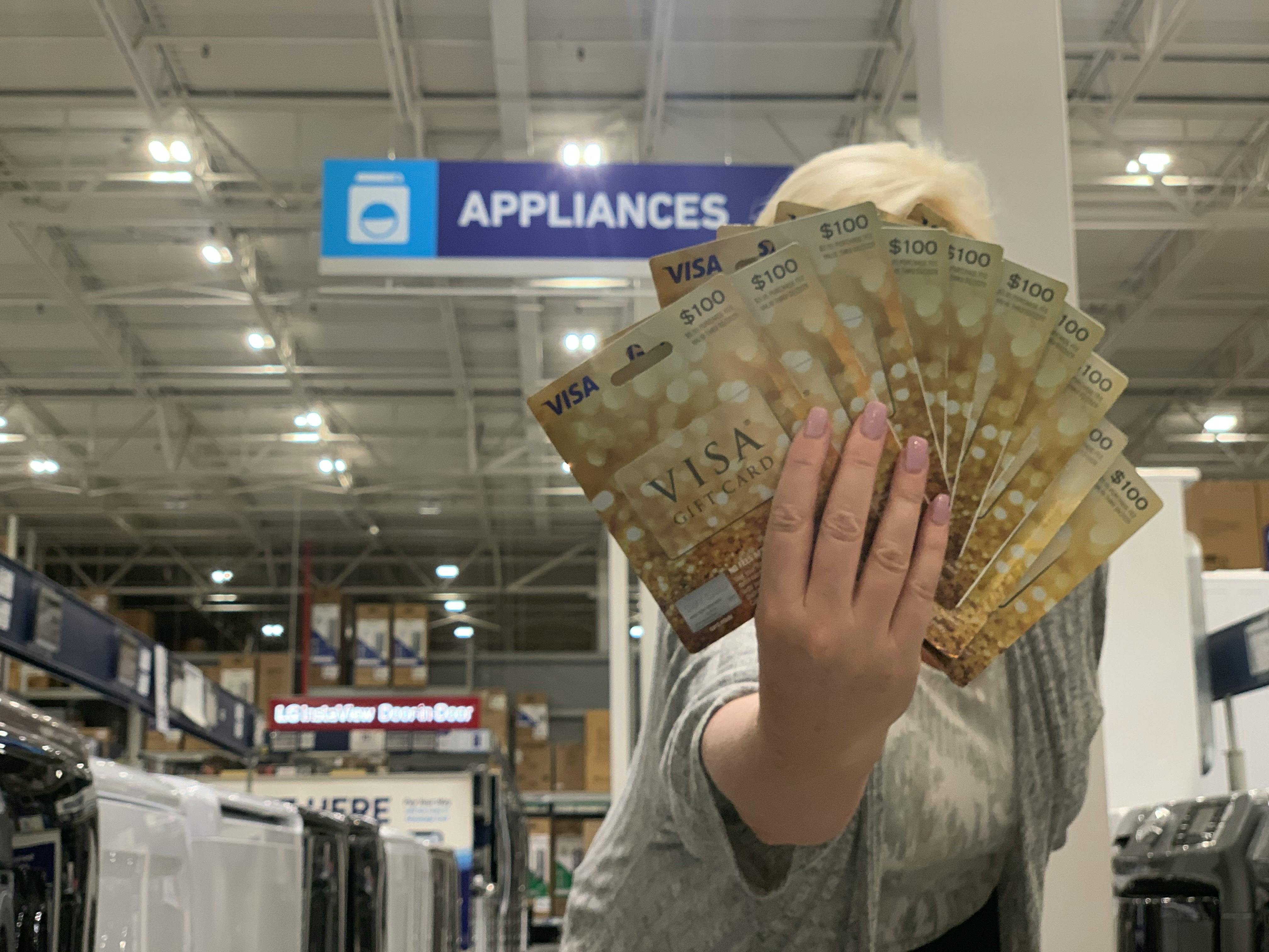 person holding many visa gift cards in applainces sign