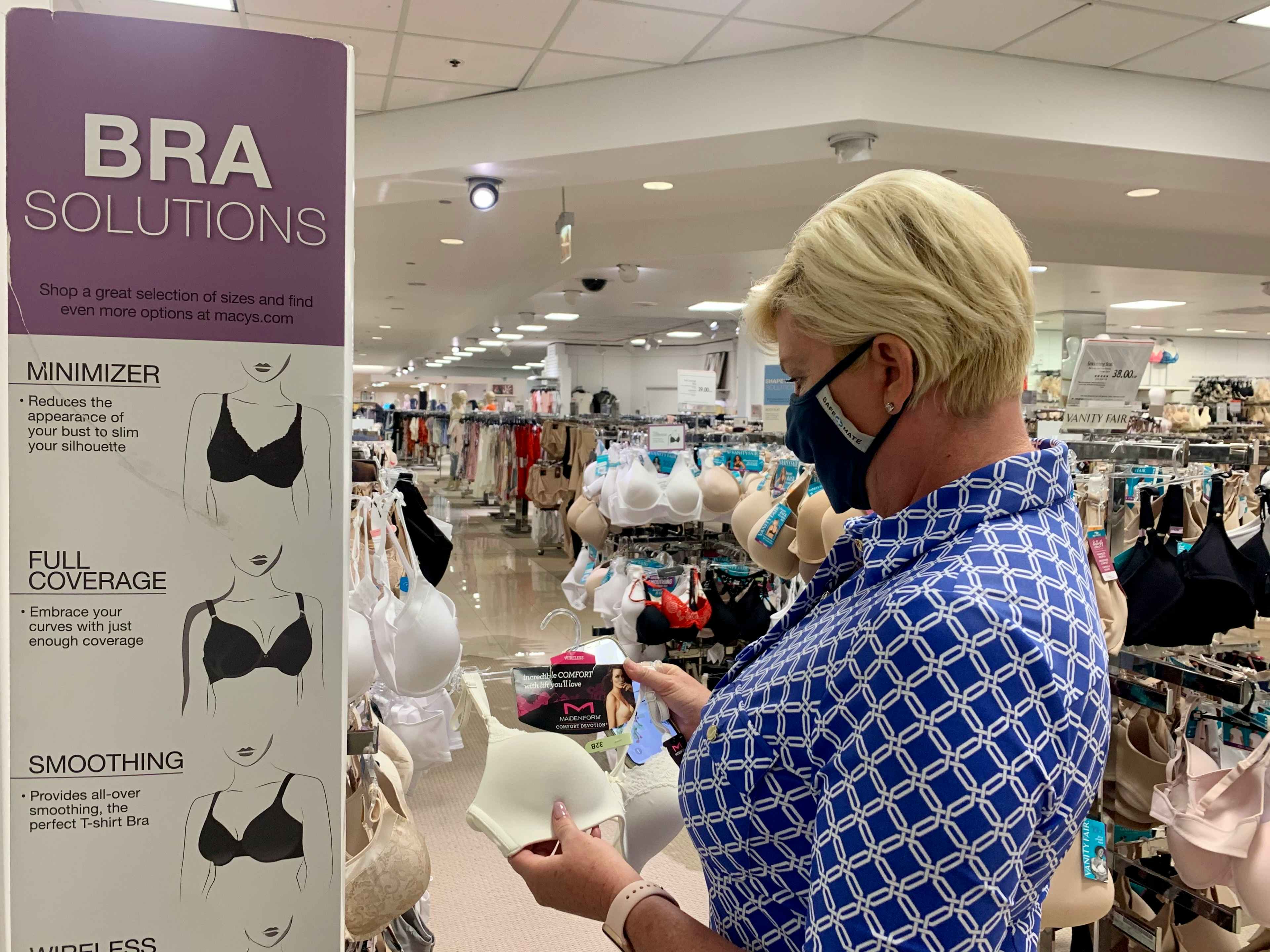 woman looking at a bra next to a bra solution sign