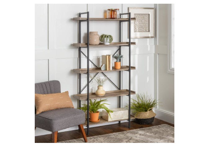 An industrial bookcase with books and vases on the shelves.