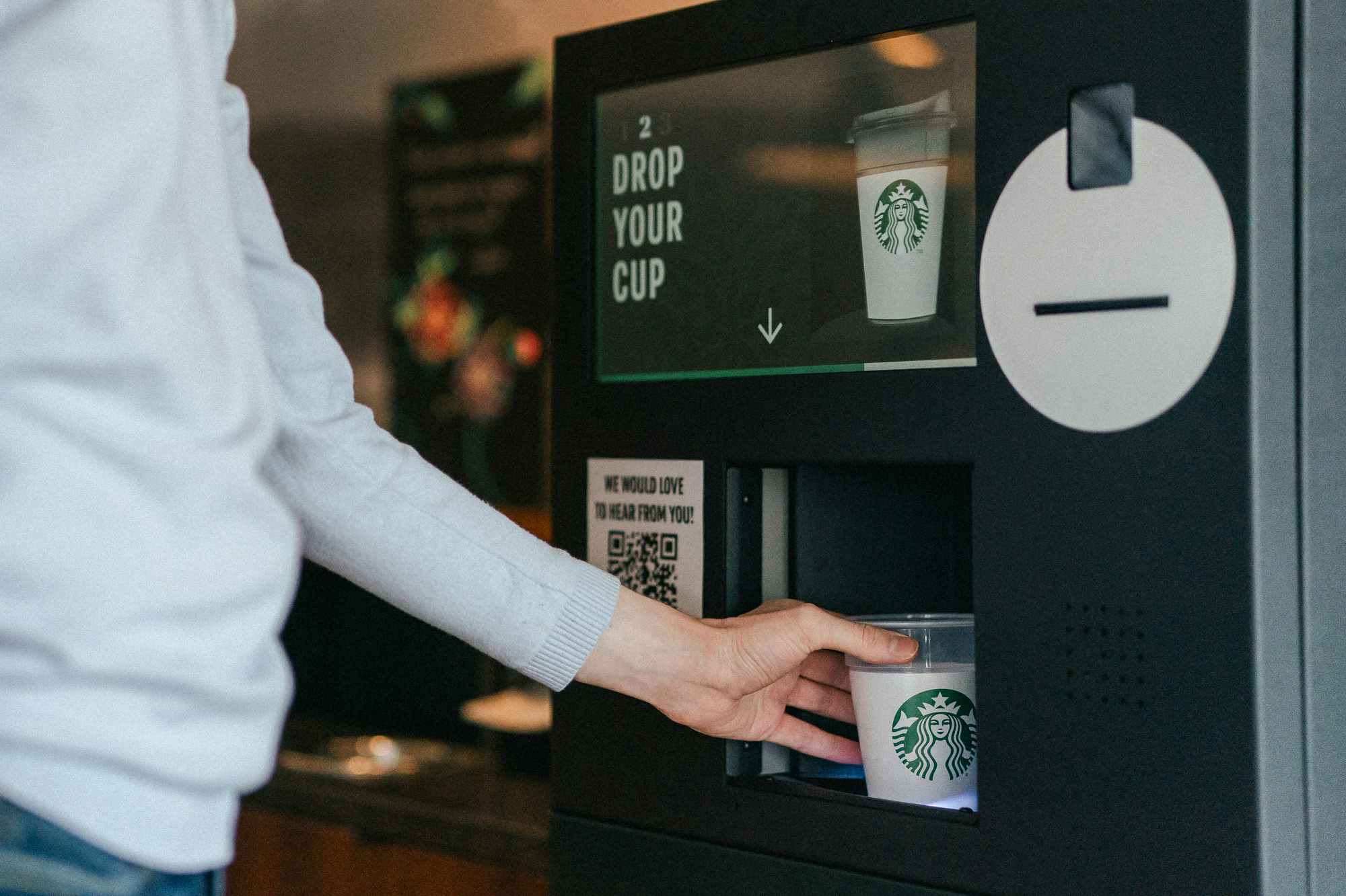 someone putting their cup into a machine at Starbucks