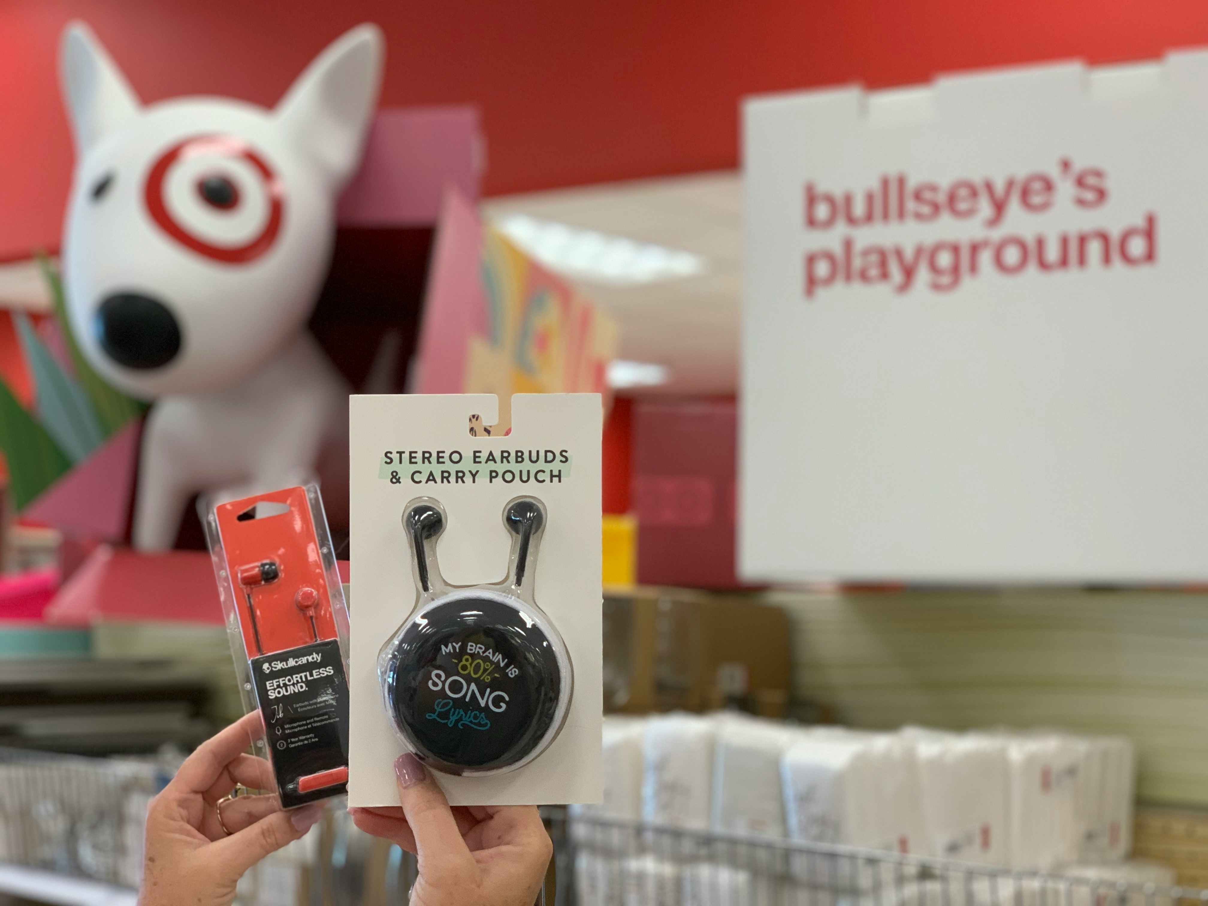 hands holding earbud headphones in front of bullseyes playground display in target store