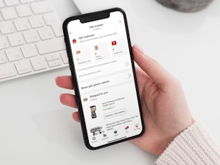 a hand holding a phone open to the target app, showing the gift tracker on the target wedding registry page