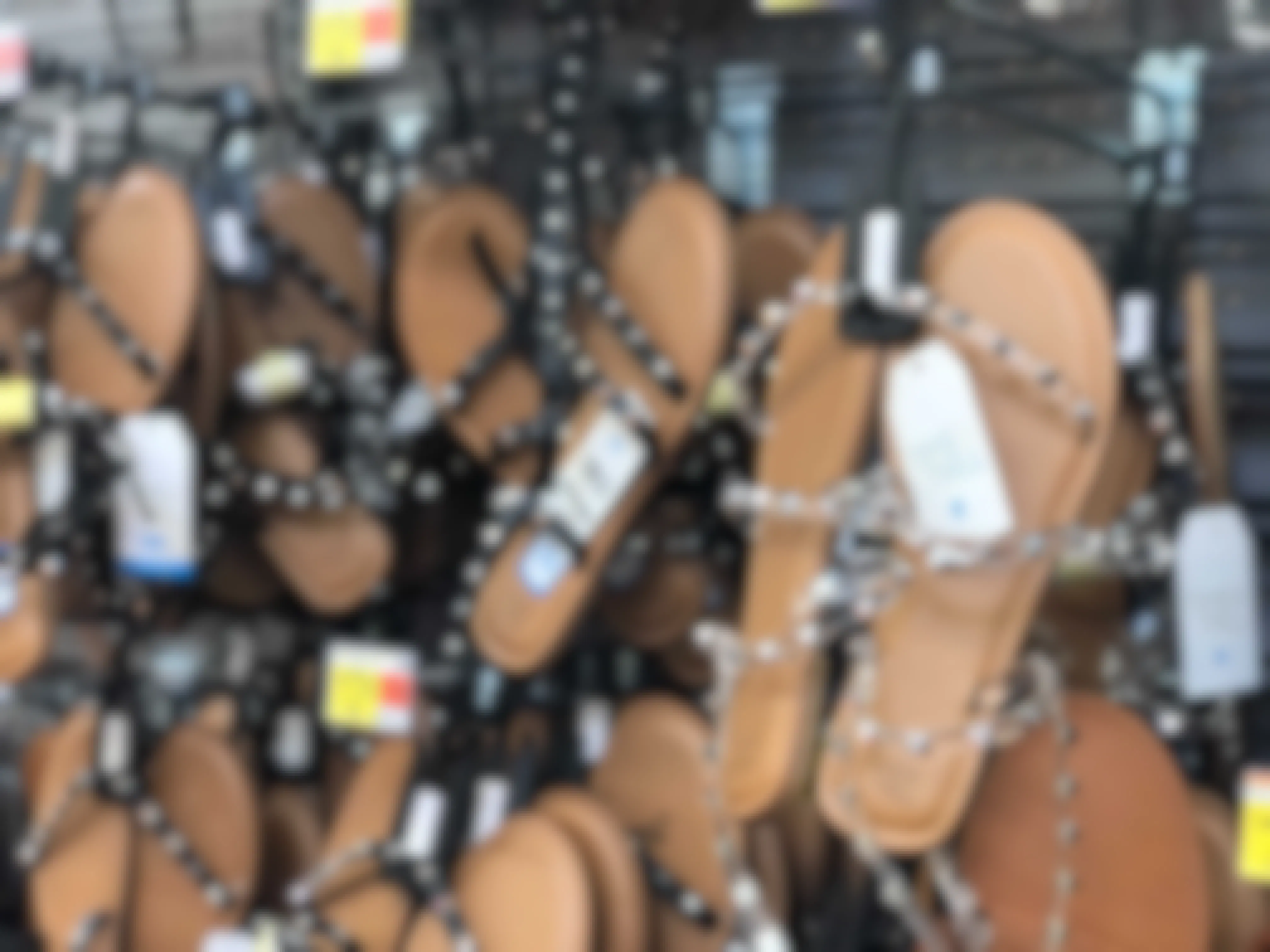 Several pairs of sandals hanging from store racks.