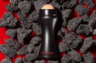 A Revlon volcanic face roller laid on top of volcanic rocks