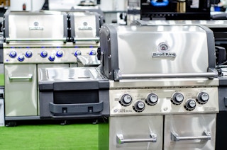 There is a grill labeled Broil King in front of another larger grill.