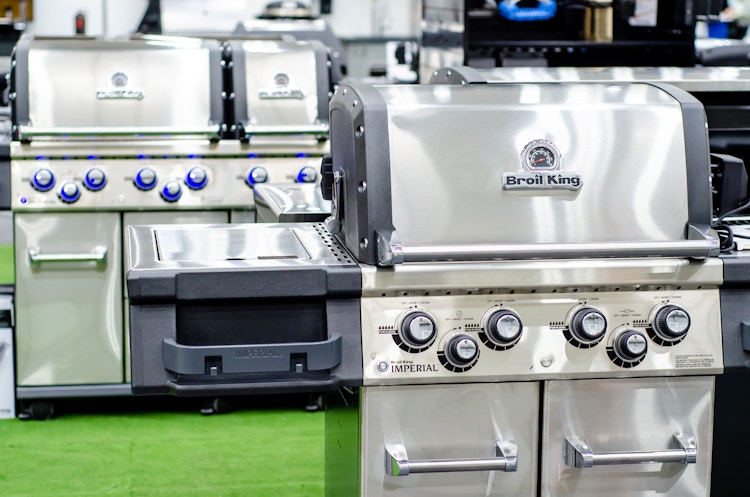 There is a grill labeled Broil King in front of another larger grill.