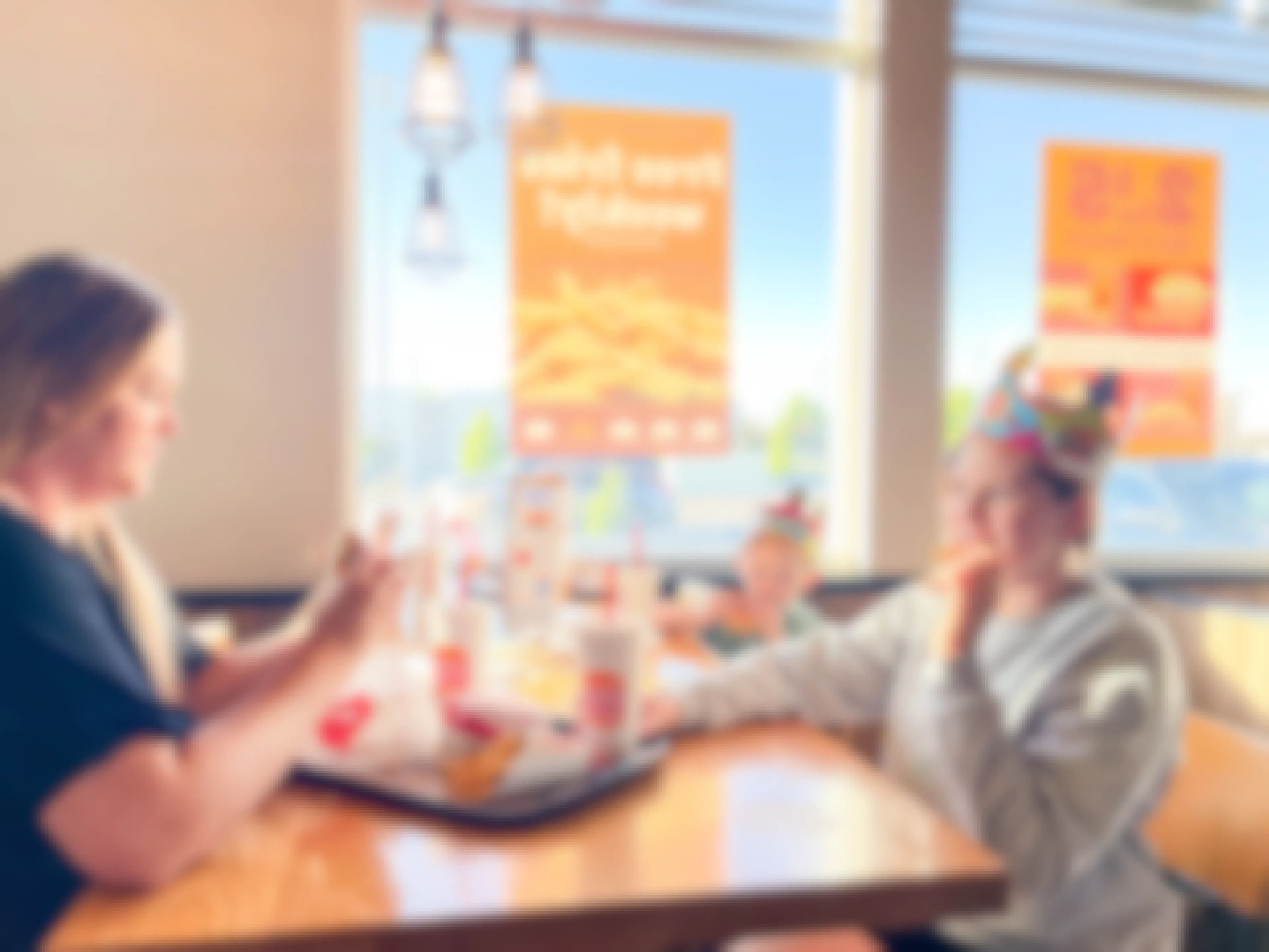 a woman and two kids eating at a table inside burger king