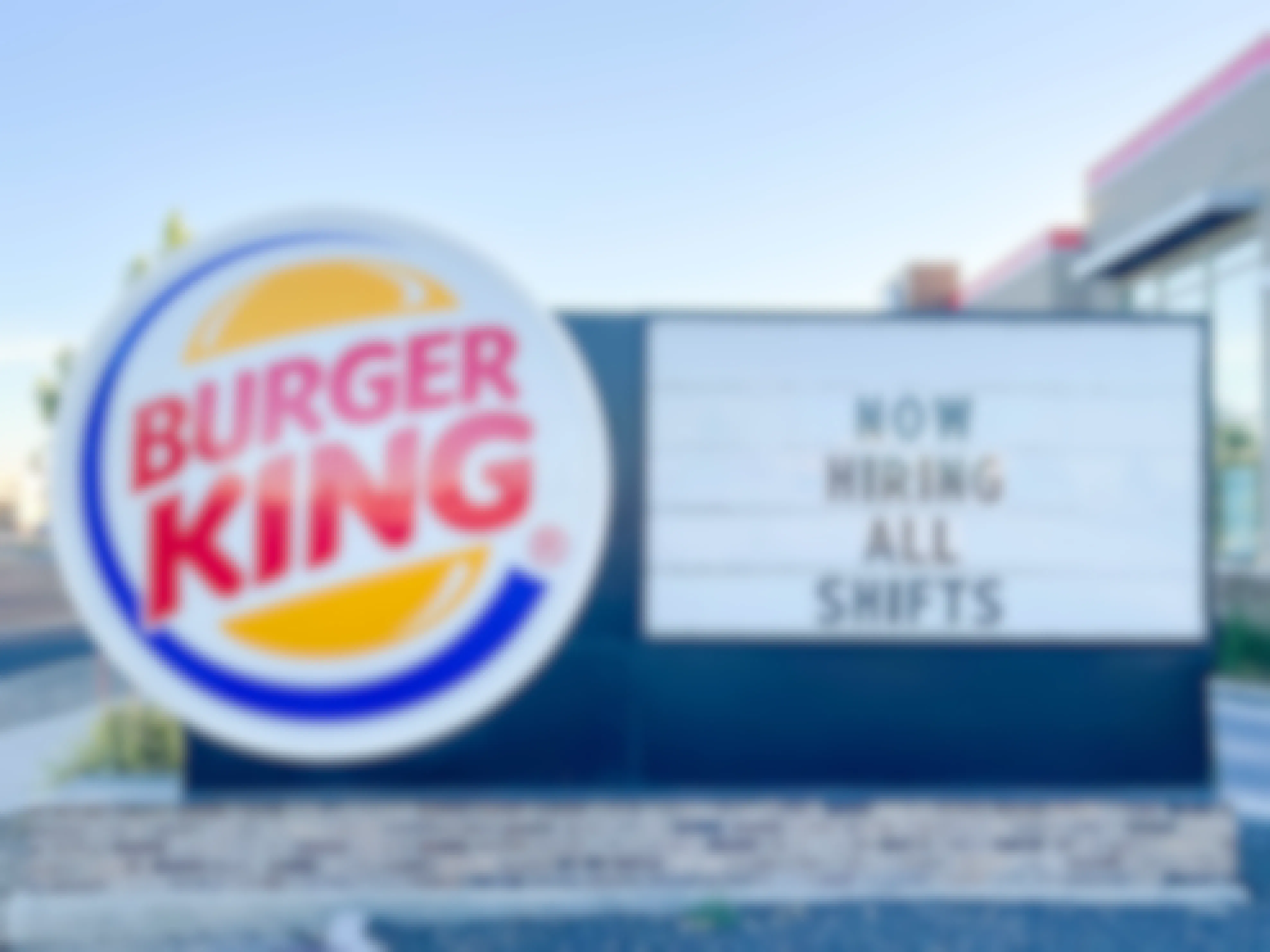 a large outside burger king sign with hiring all shifts sign
