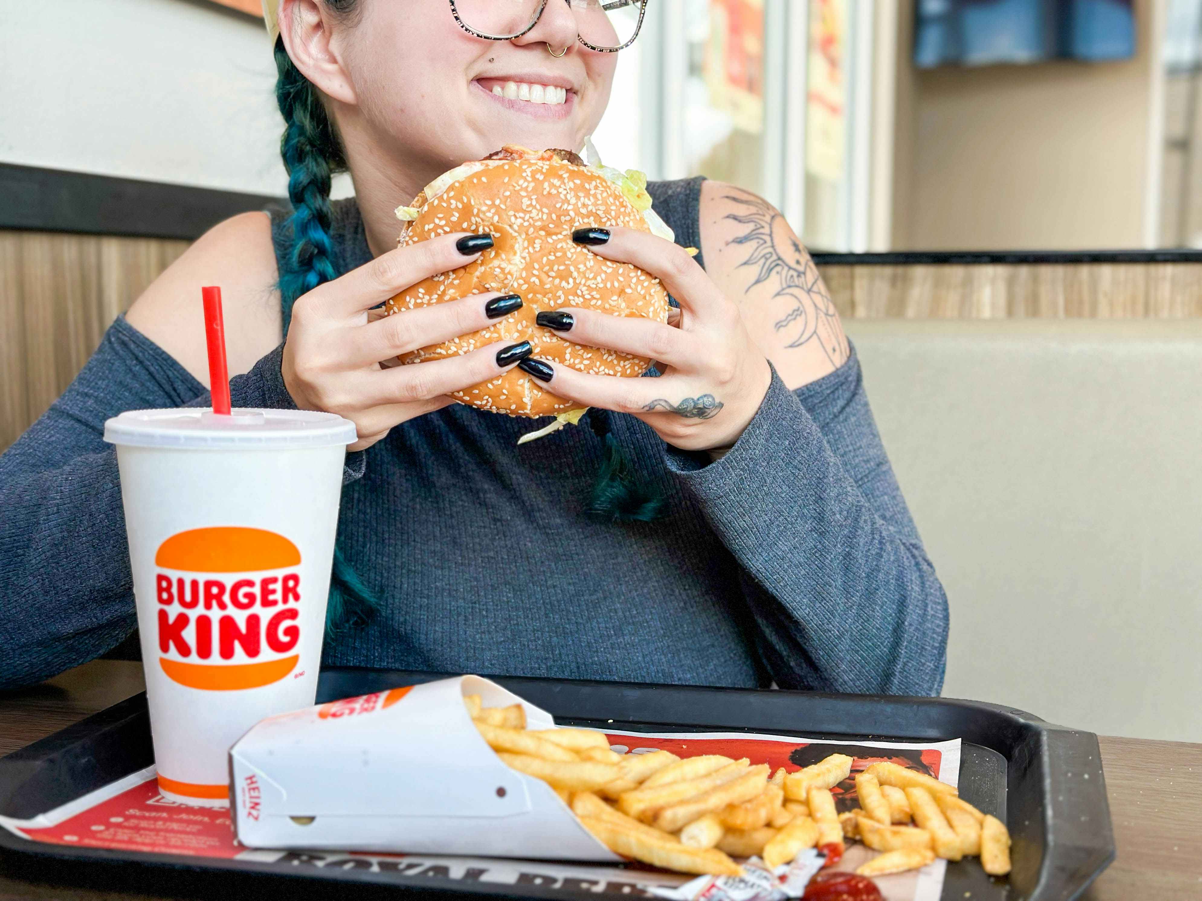 a woman holding a whopper in burger king 