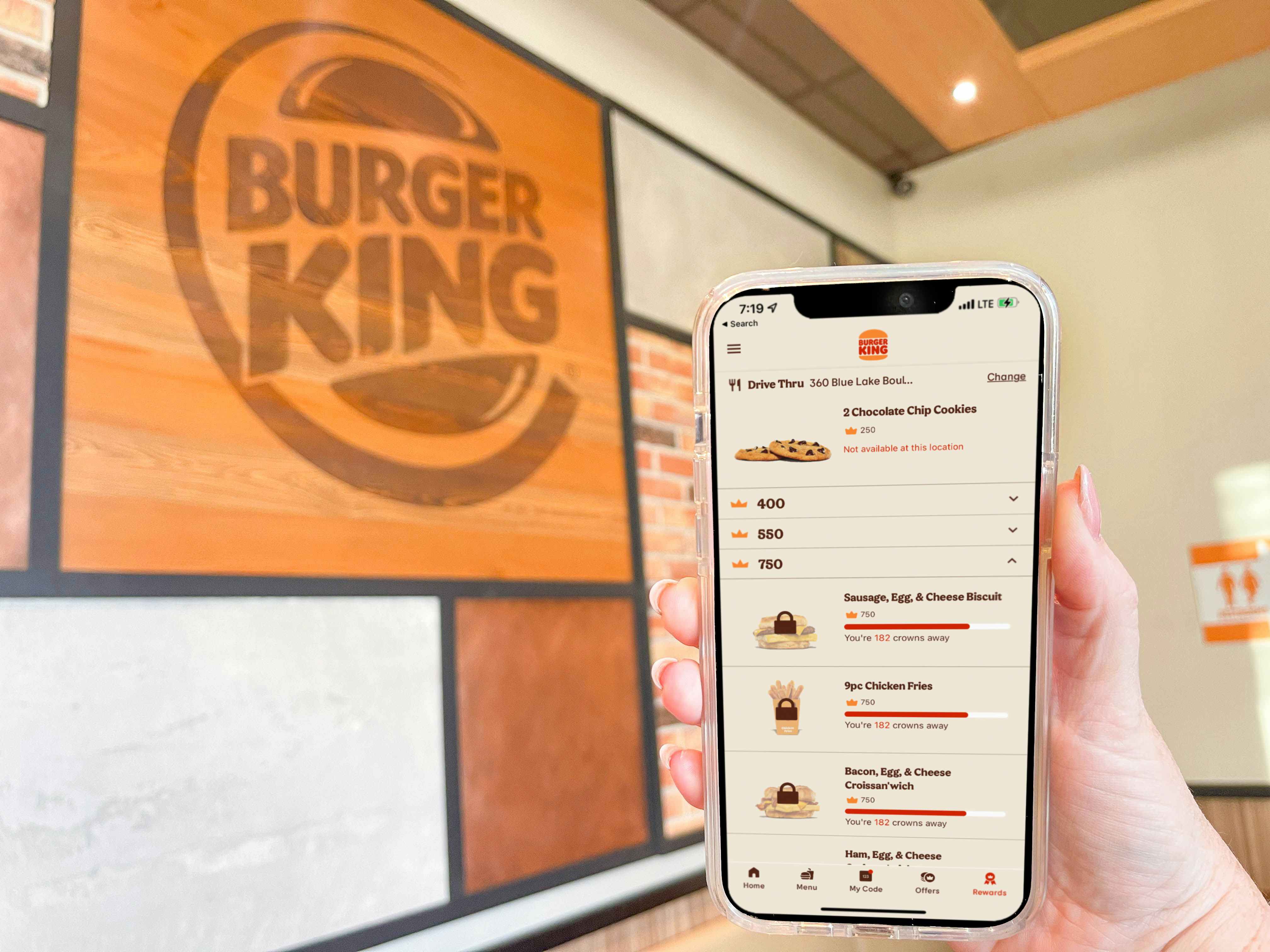 a cellphone being held up with burger king app inside store
