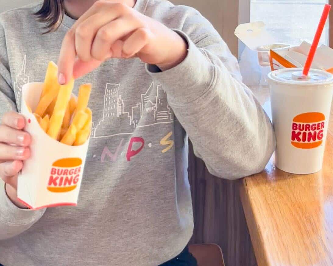 a person pulling a fry out of a burger king fry box