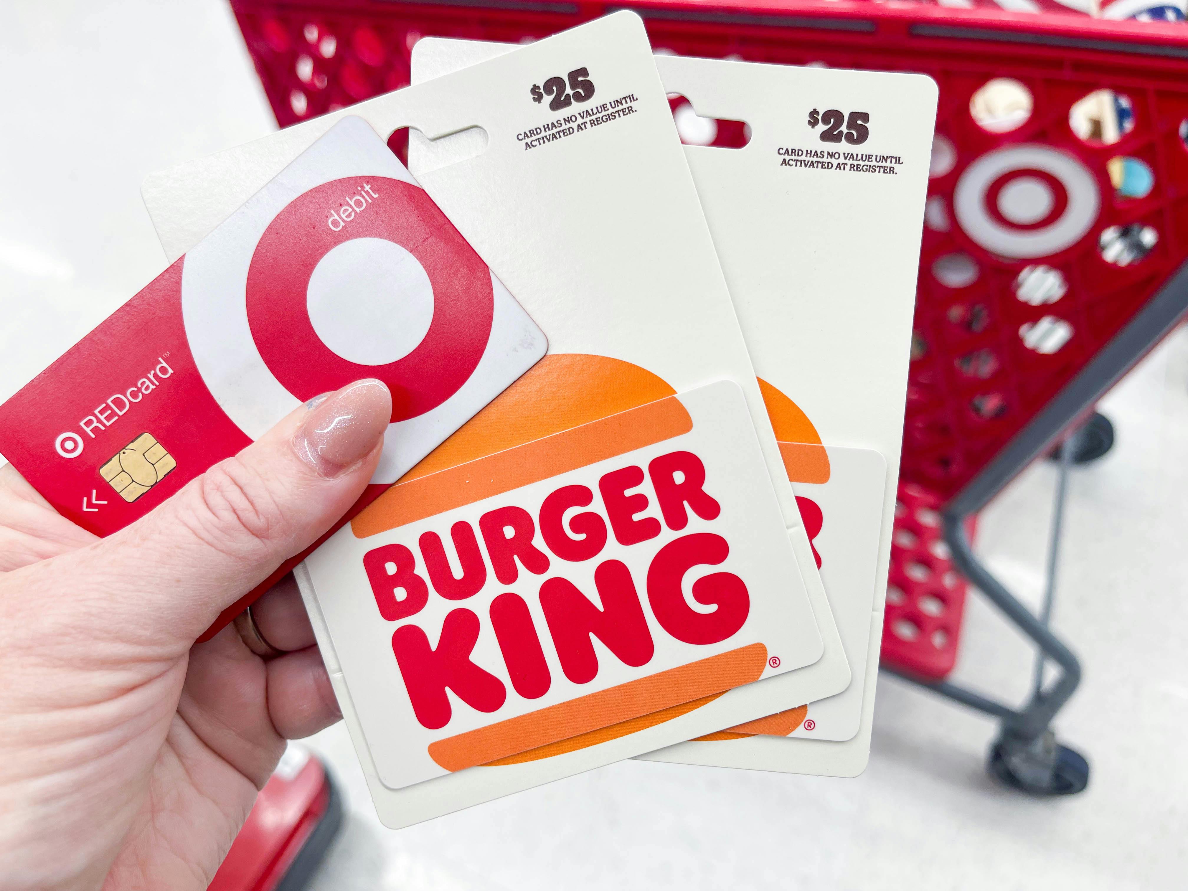 two burger king gift cards and a target red car being held near a target cart
