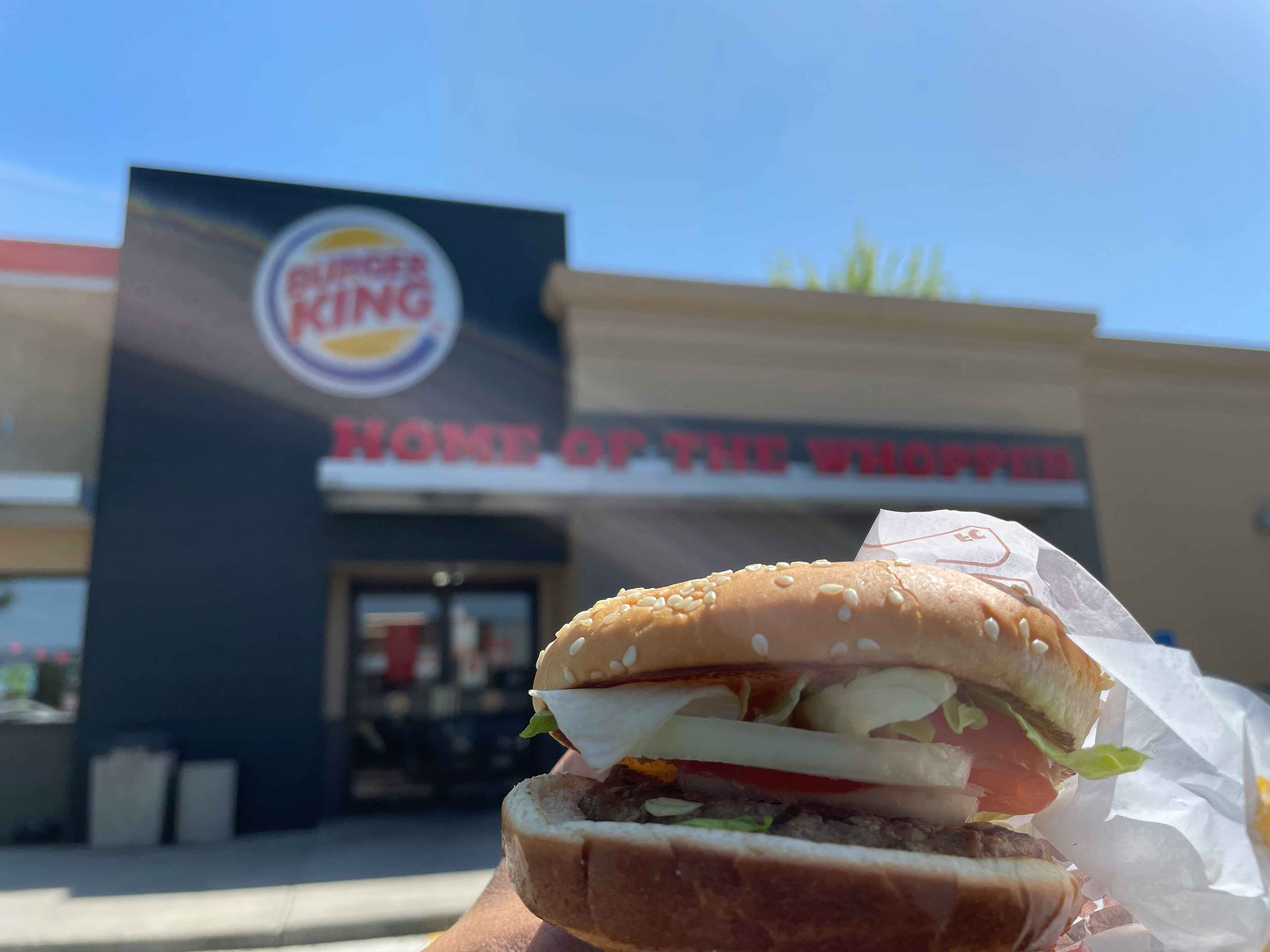 a person holding up a whopper from burger king