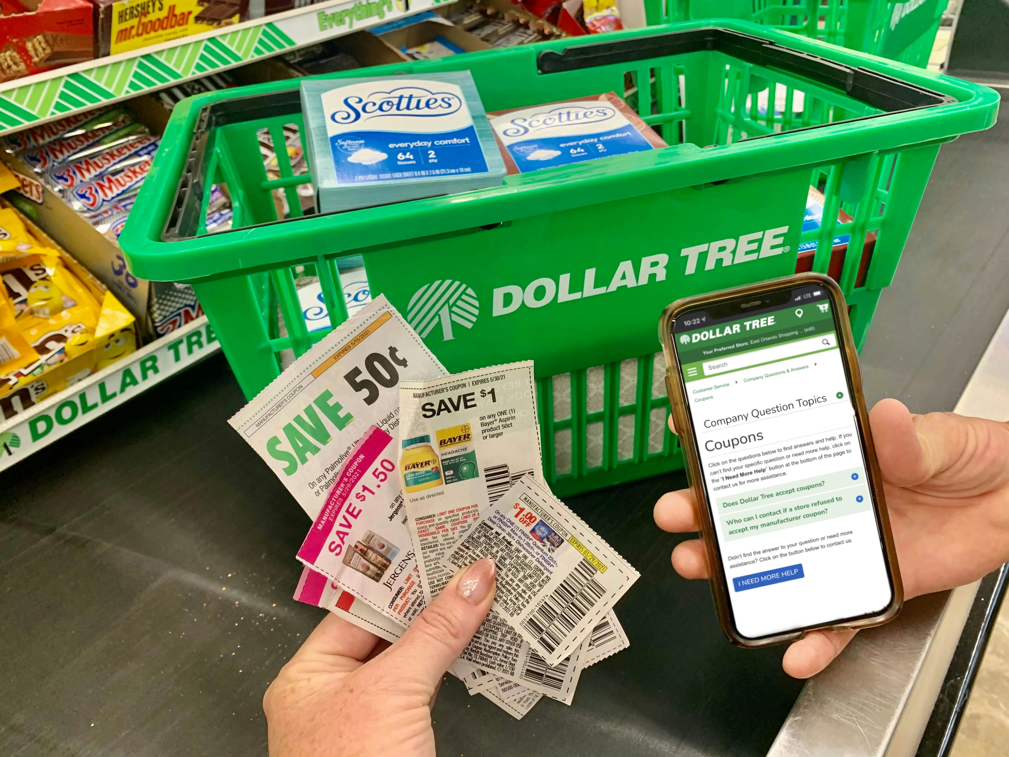 hands holding coupons and a cellphone showing Dollar Tree's coupon policy next to a Dollar Tree basket at checkout