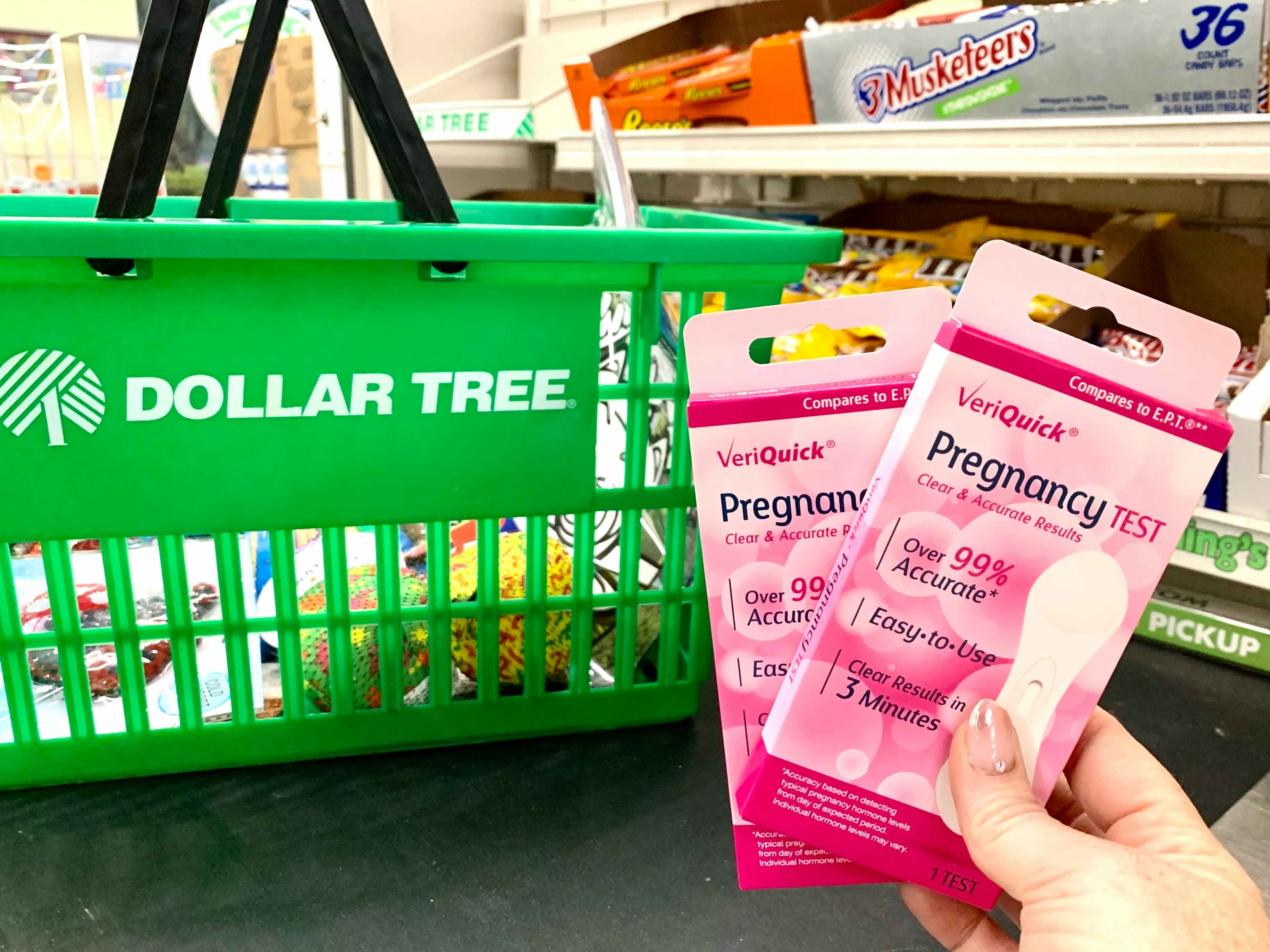 someone holding pregnancy tests in front of Dollar Tree basket