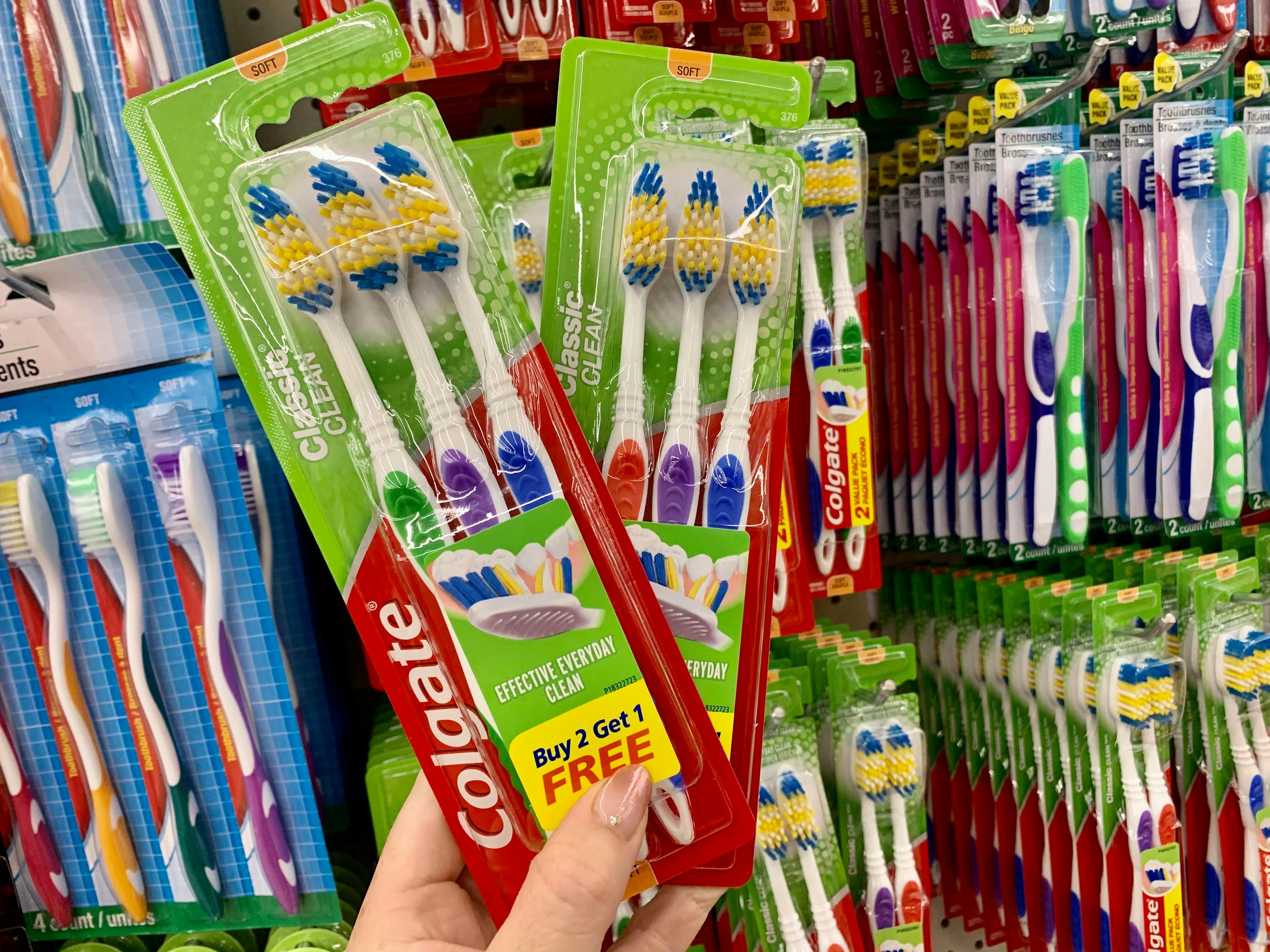 2 packages of toothbrushes being held up together at Dollar Tree