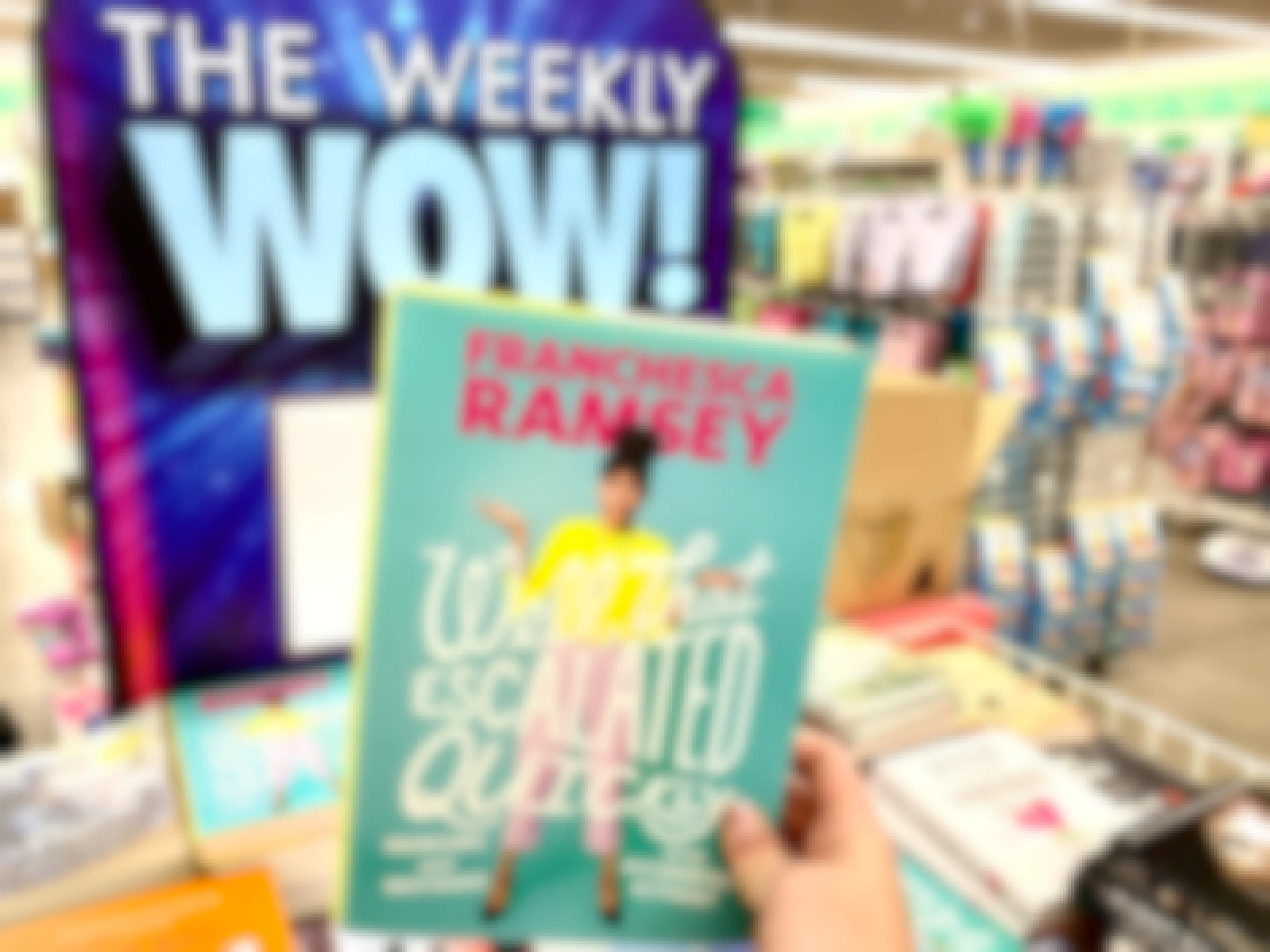 a book being held in front of the weekly wow sign in the Dollar Tree store