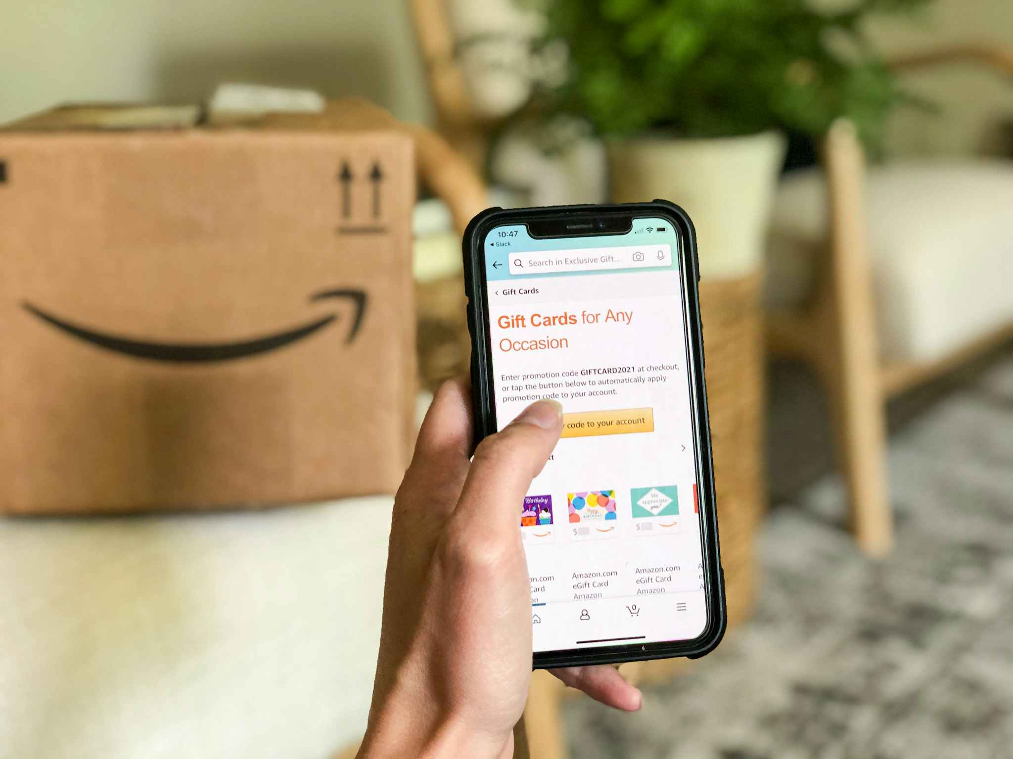 person holding phone in front of Amazon box