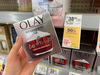 hand holding olay in front of sale sign