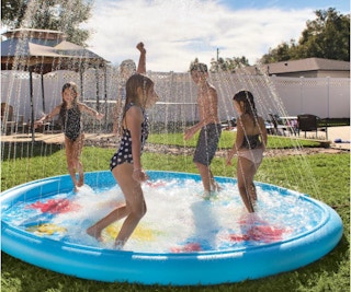 Kids playing in a splash pad pool outside.