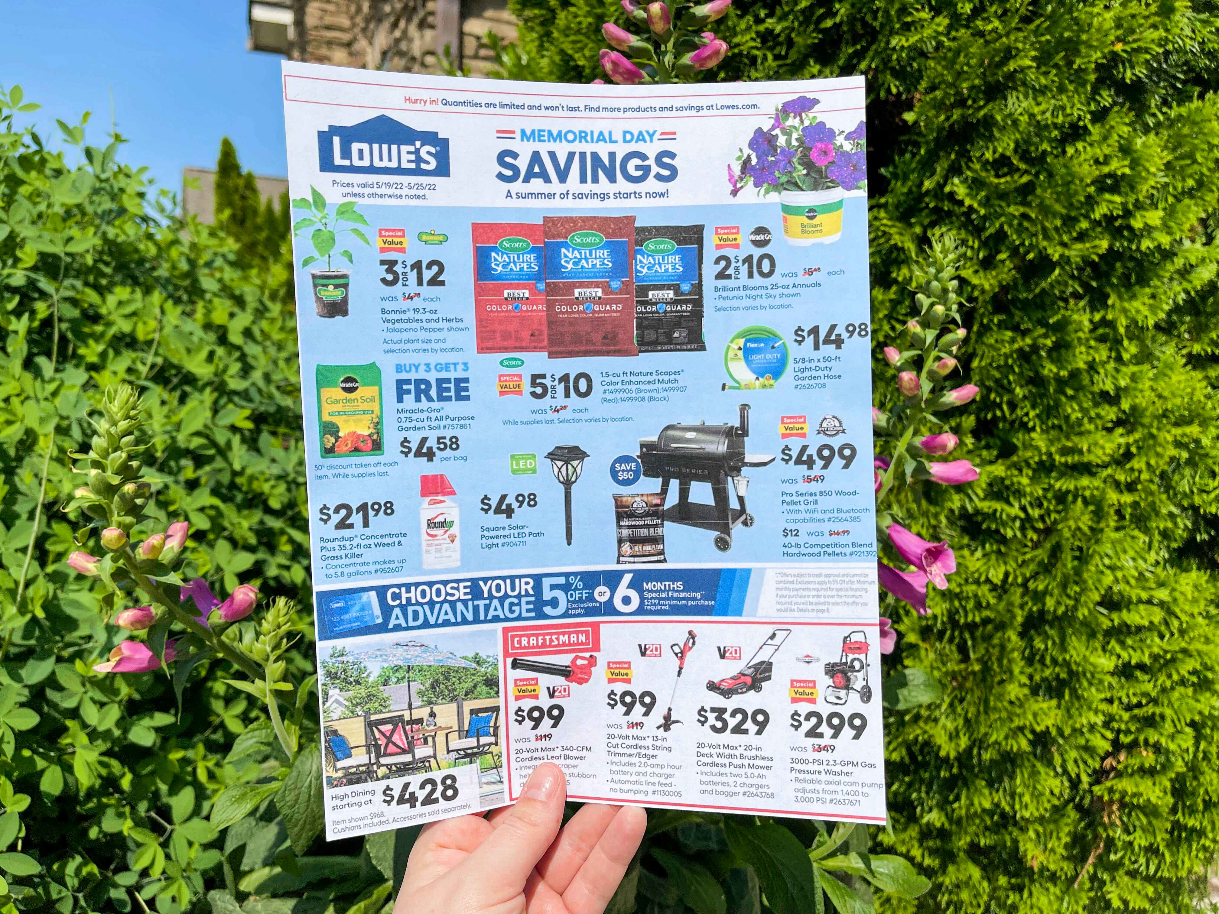 A person's hand holding up a Lowe's savings ad for the Memorial Day sale