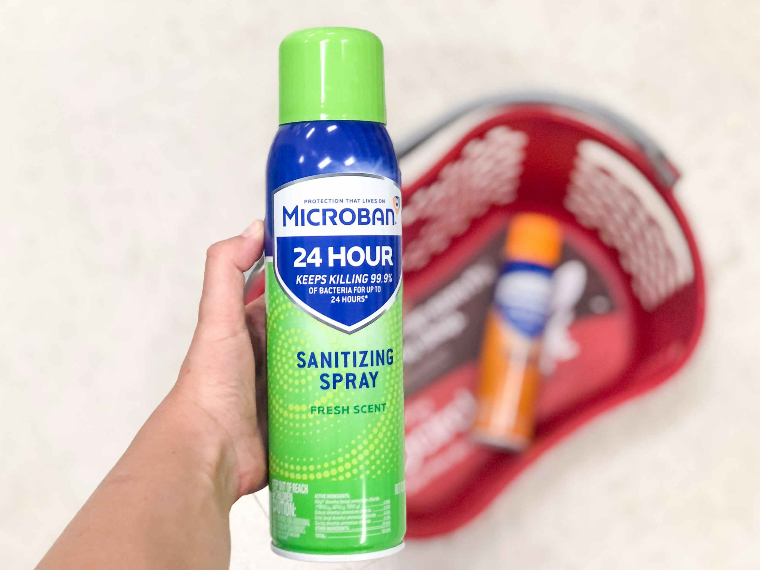 hand holding bottle of sanitizing spray over a store basket