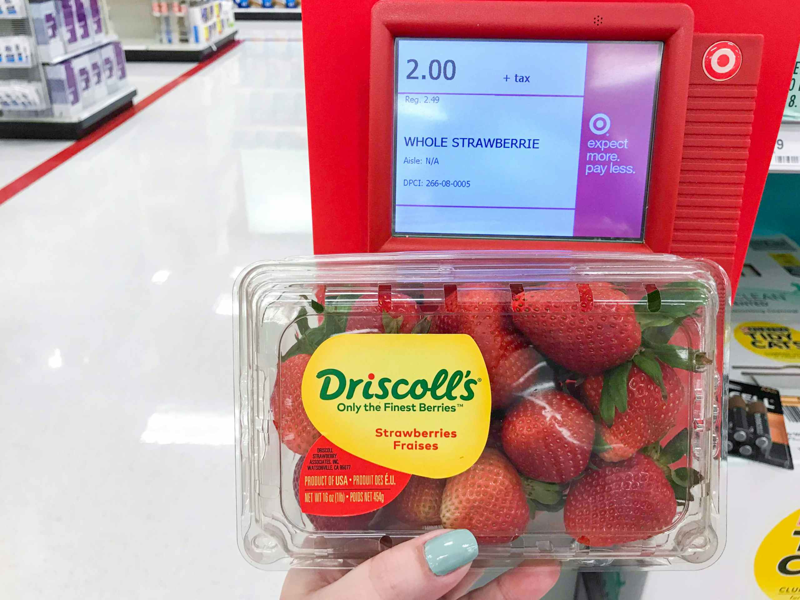 hand holding carton of strawberries with price