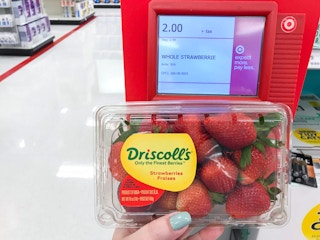hand holding carton of strawberries with price