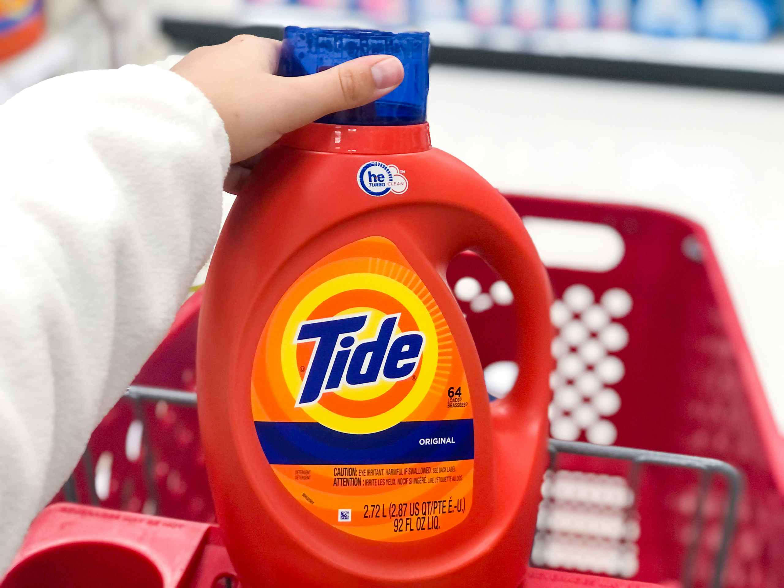 hand holding lid o detergent bottle in shopping cart