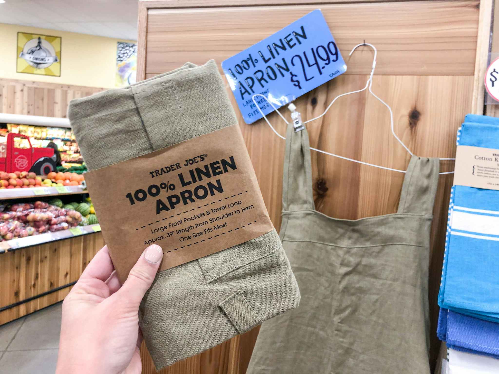 Linen apron in packaging held in front of price tag in Trader Joe's